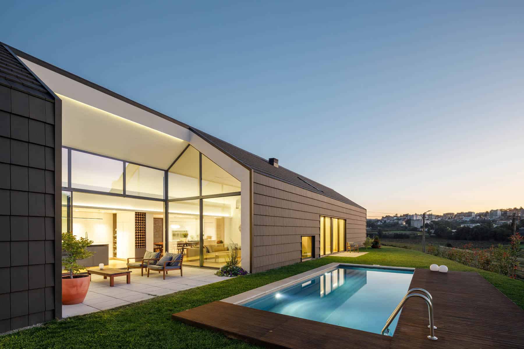 Modern minimalist house with large glass windows and outdoor swimming pool at sunset. Sleek contemporary architecture emphasizes open space, natural light, and stylish outdoor living area.