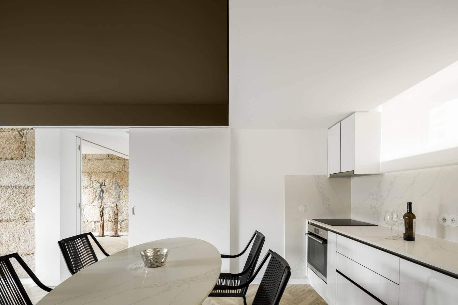 Sleek modern kitchen with minimalist white cabinetry, marble countertops, and contemporary decor. Bright natural light enhances the clean, stylish design perfect for luxury interior architecture.