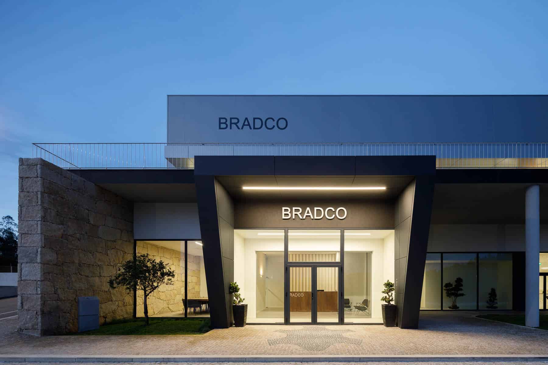 Modern commercial building with sleek architectural design and illuminated signage for Bradco, featuring contemporary materials like glass and stone, ideal for corporate or retail spaces.
