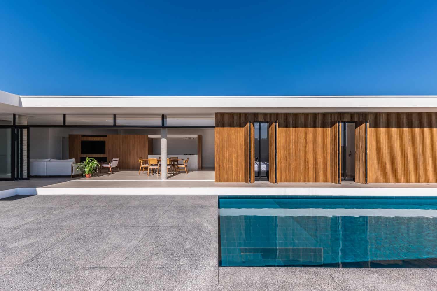Contemporary residential house with modern architecture, wooden sliding doors, outdoor pool, and minimalist design, featuring sleek lines and open-plan living spaces.