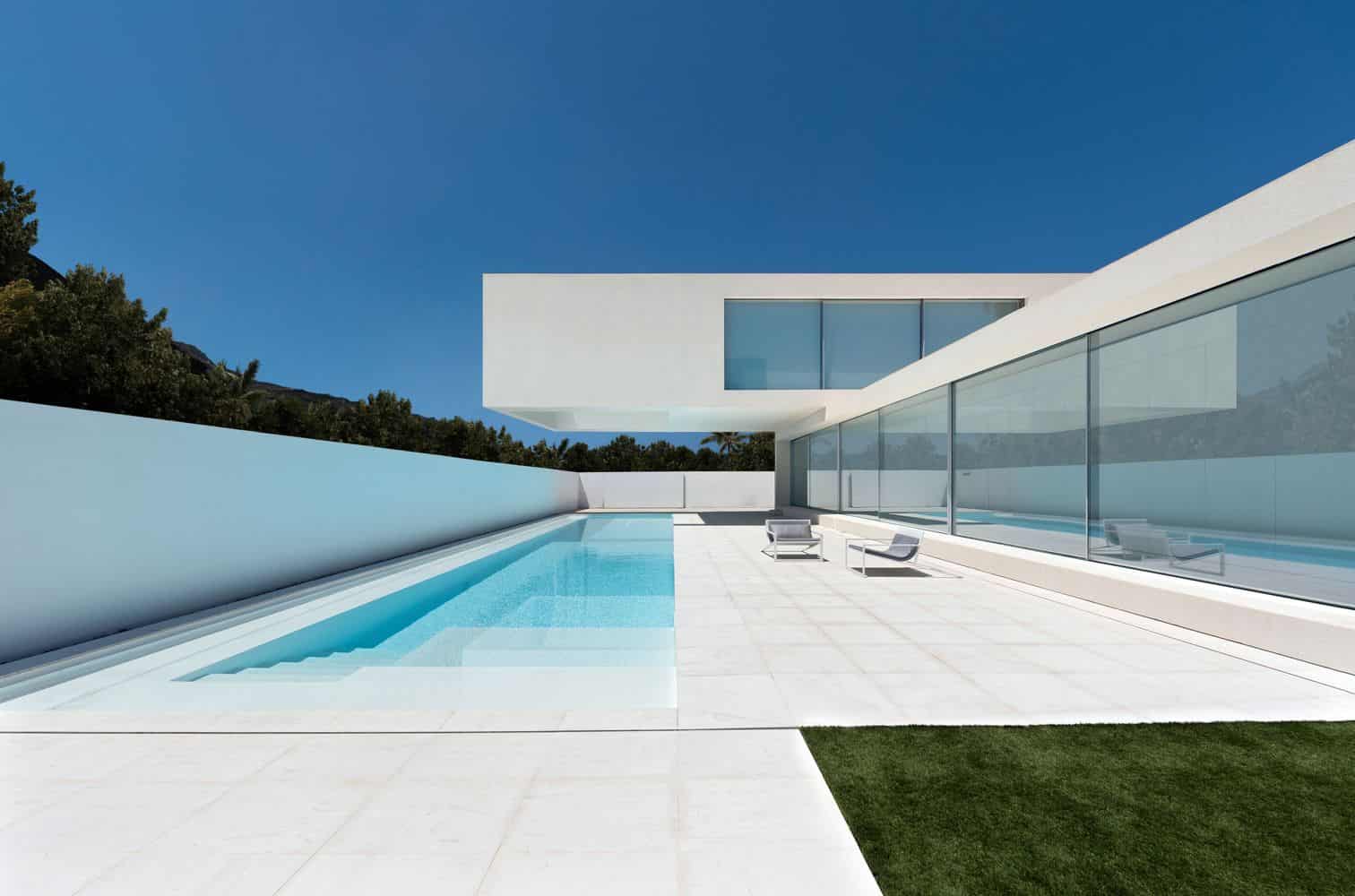 Contemporary modern minimalist house with glass walls and swimming pool, luxury architecture design, elegant outdoor space, clean lines, and sleek white exterior for luxury home appeal.