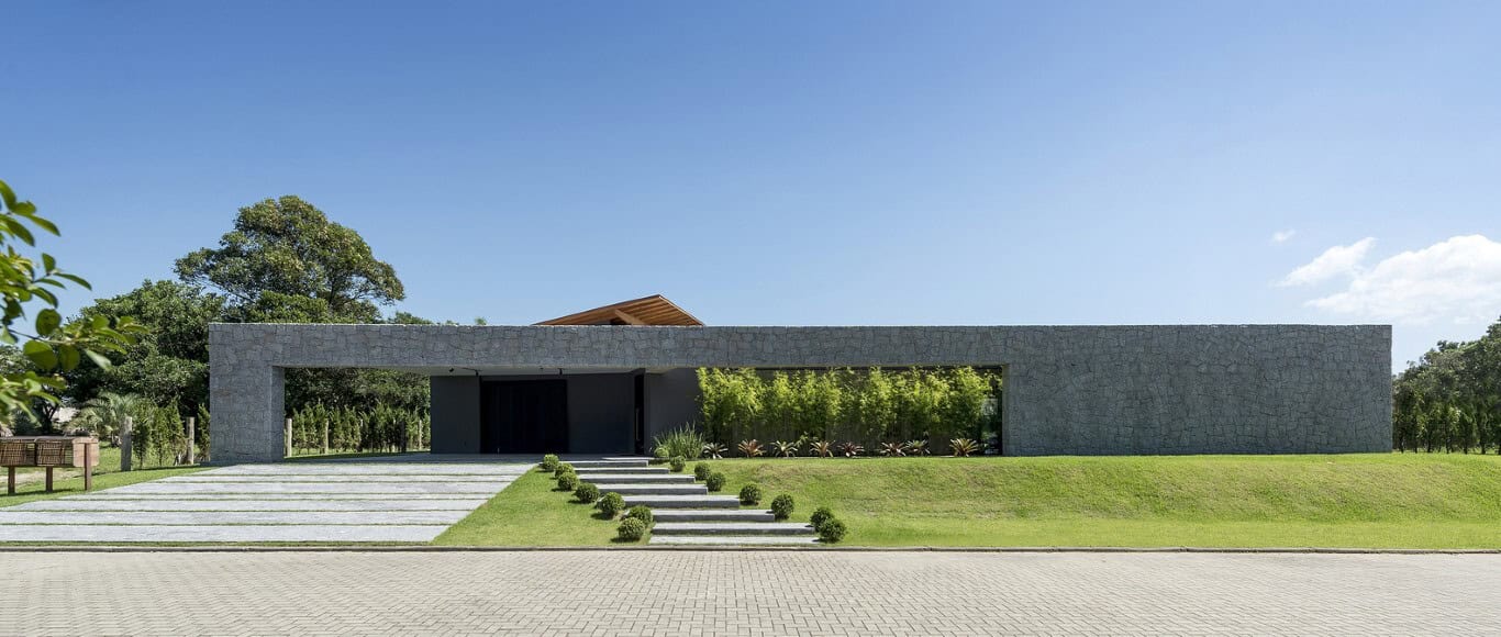 Modern minimalist concrete house with sleek design and landscaped front yard, set against a clear blue sky.
