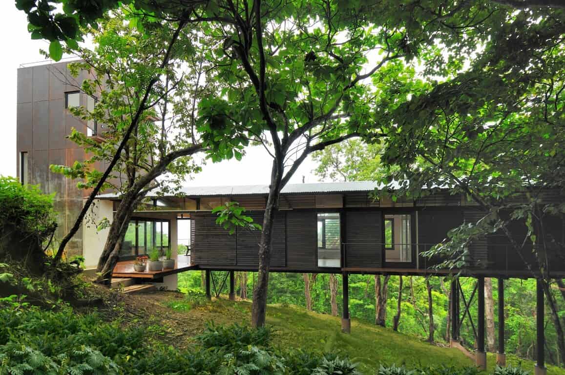 Modern eco-friendly treehouse with sleek wooden design and large windows nestled in lush green forest, offering sustainable architecture and scenic nature views.