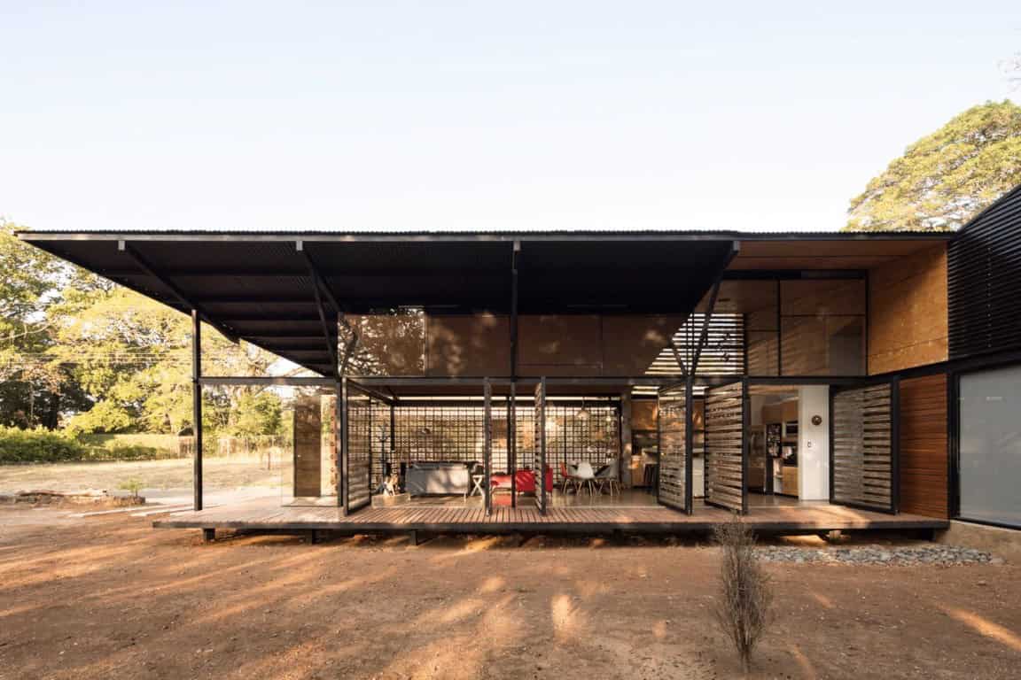 Modern minimalist house with open-plan living space, contemporary architecture, and outdoor deck in natural surroundings.