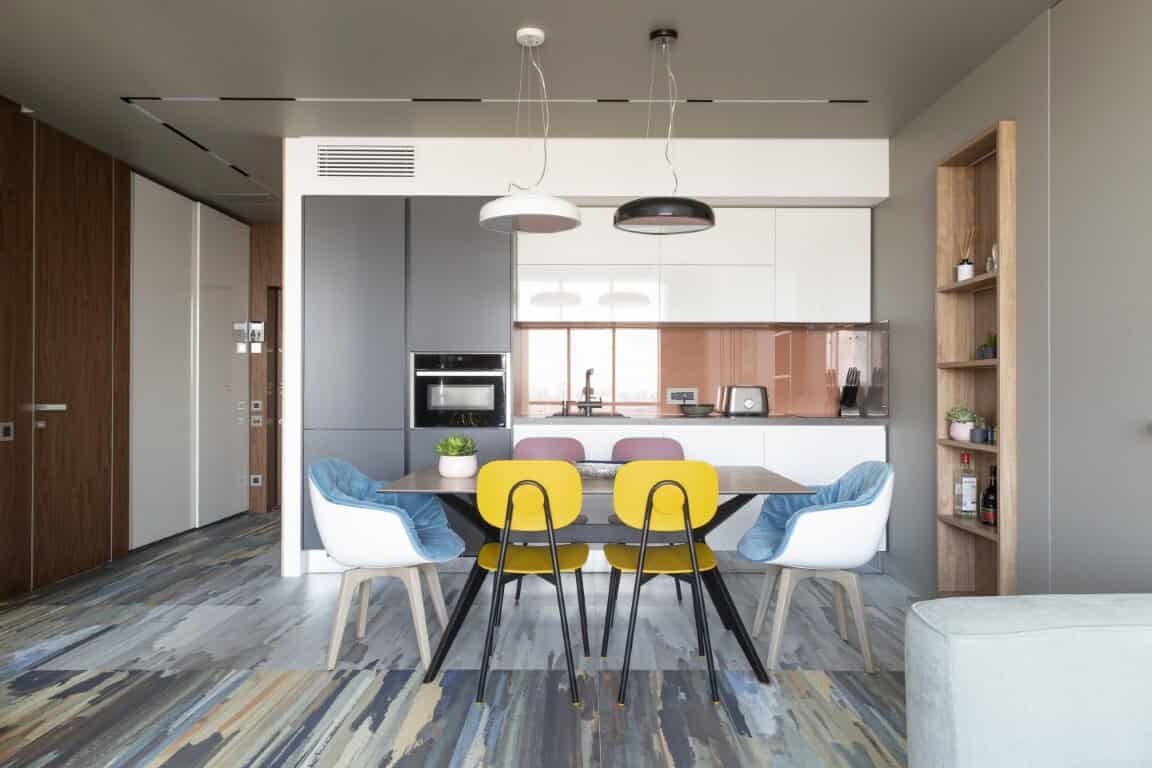 Bright modern dining room with colorful chairs and open kitchen, stylish contemporary interior design, minimalist decor, natural lighting, cozy living space, wood accents, and sleek appliances.