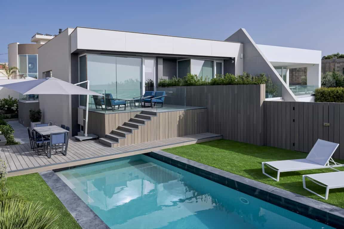Modern luxury house with backyard pool, outdoor seating, and contemporary architectural design showcasing sleek lines and open spaces.