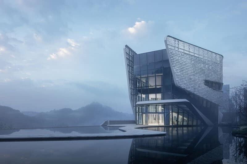 Modern architecture building with unique glass and metal design reflecting water and sky, showcasing innovative architectural art and urban design.