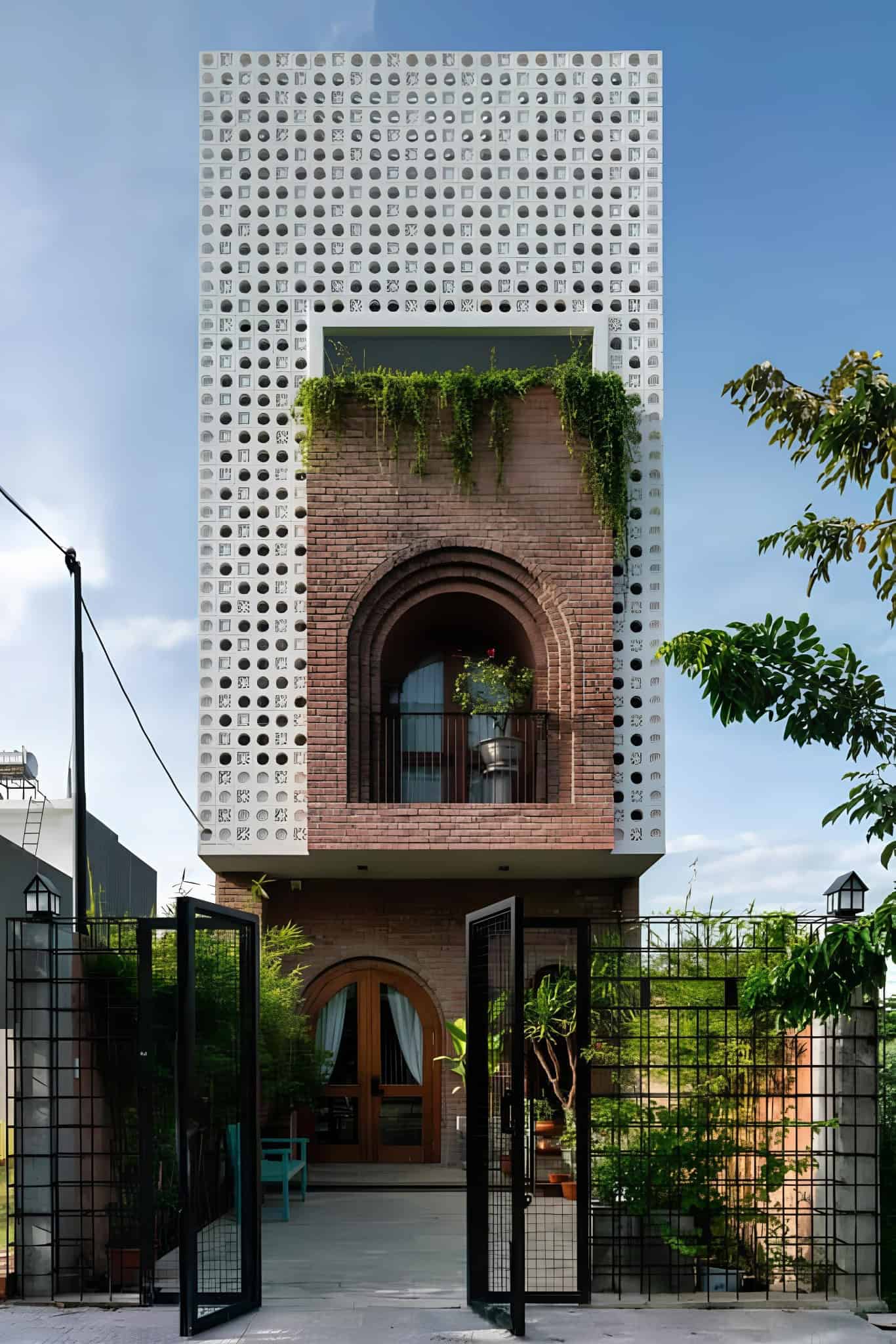 Contemporary Brick House with Decorative Screens A contemporary brick house with white patterned screens and arched balconies adorned with greenery.