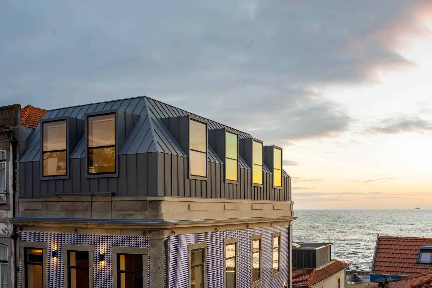 Modern coastal architecture with innovative metal roofing and large windows overlooking the ocean.
