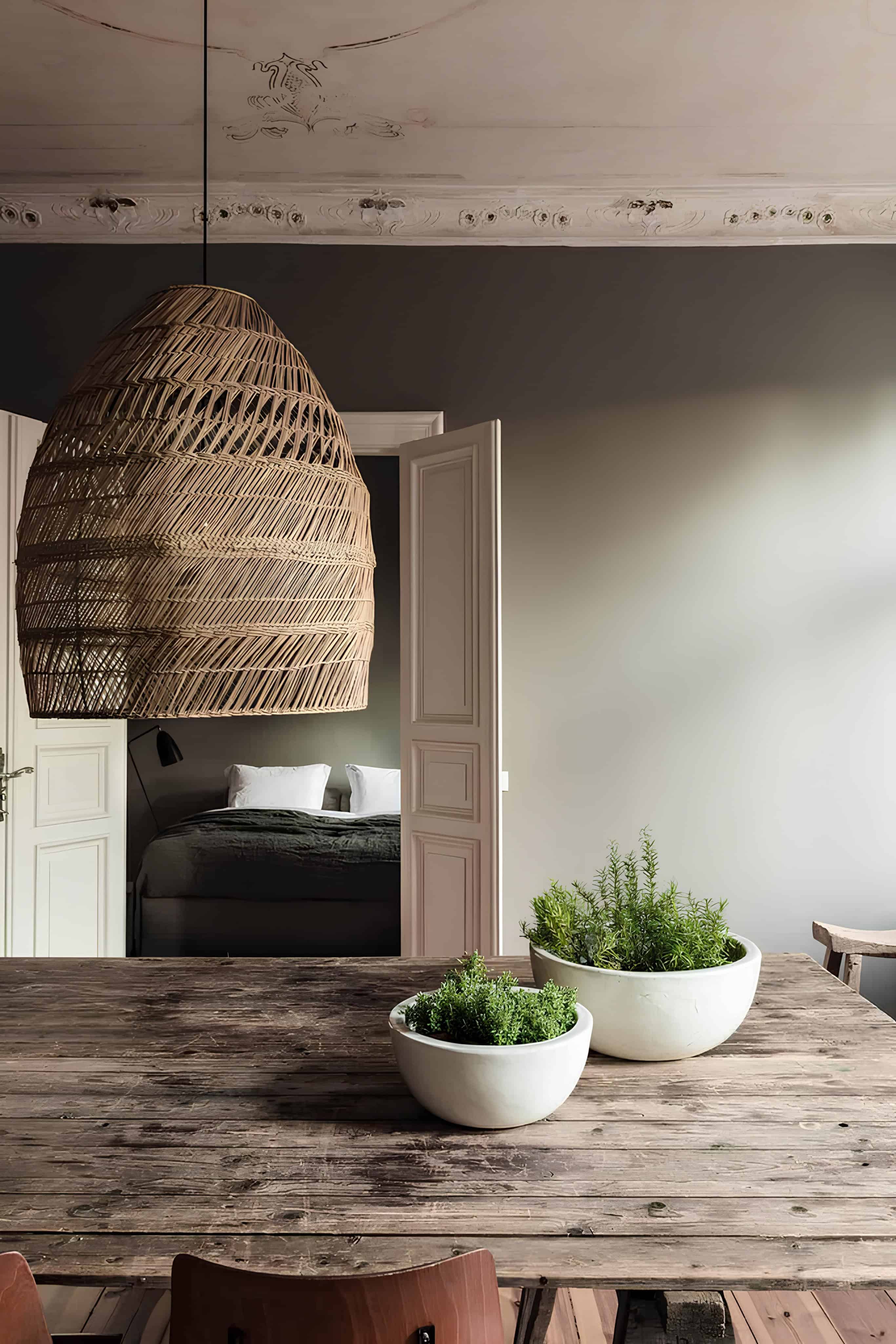 Large woven rattan pendant light over rustic wooden table in a cozy dining room