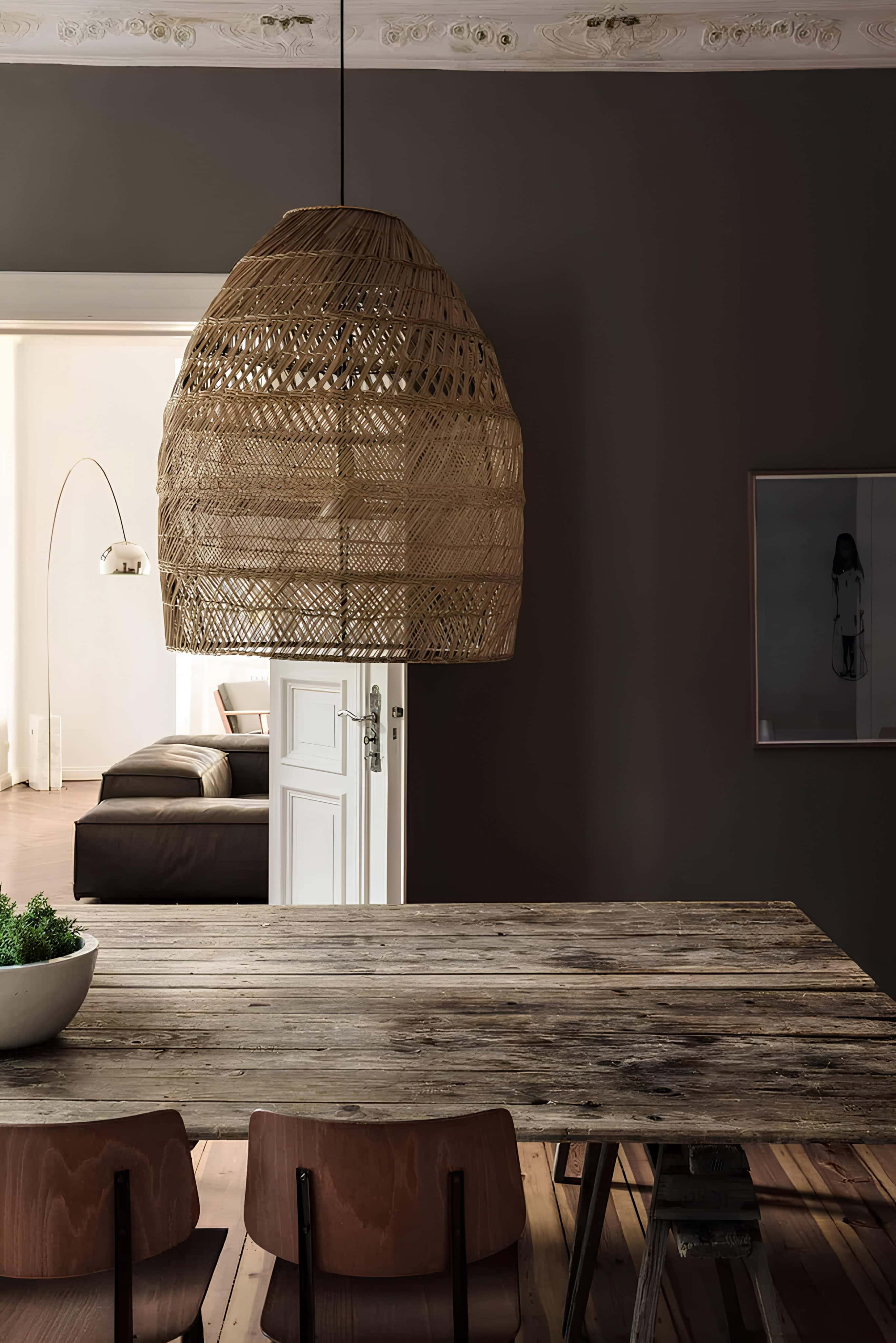 Dark green dining room featuring a natural rattan pendant lamp and rustic wood table