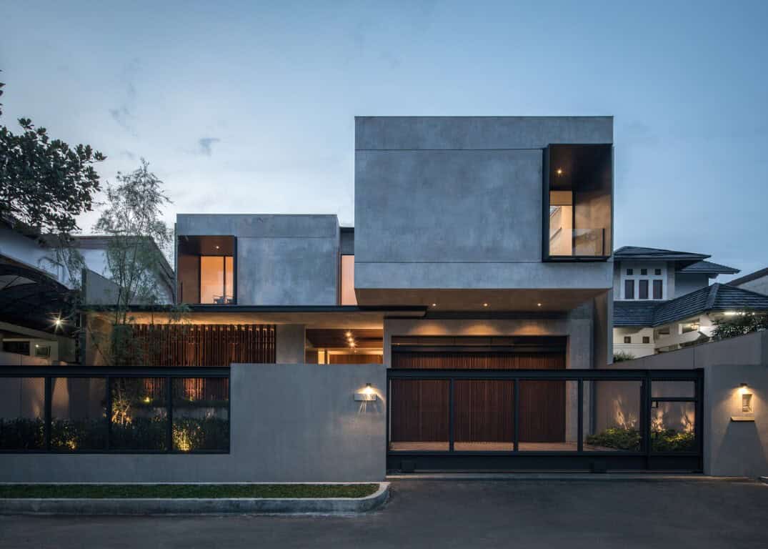 Contemporary modern house with minimalist concrete exterior and large glass windows, innovative architectural design, during dusk, featuring sleek lines and a secure gated entrance.