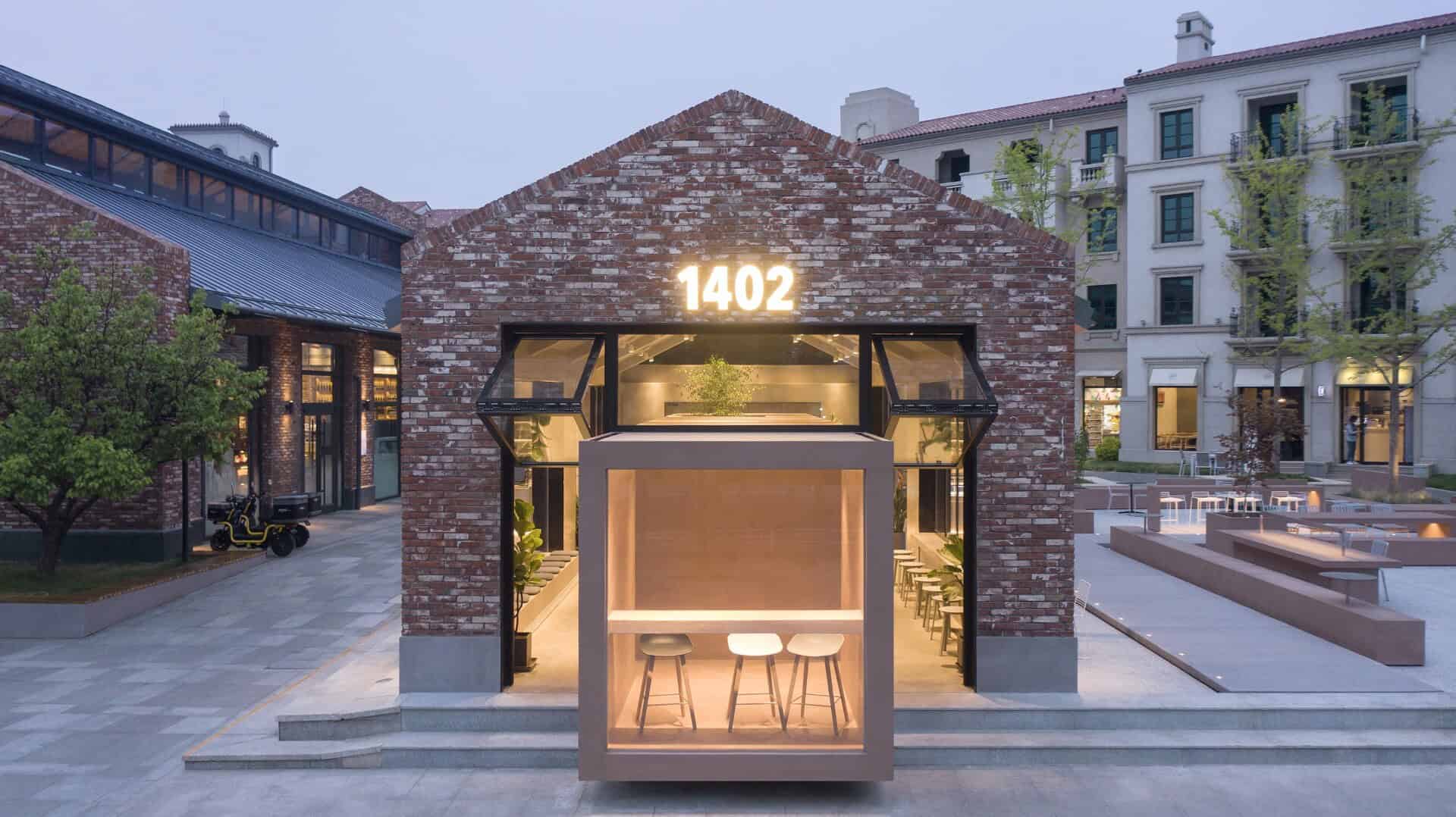 Elegant modern brick building with illuminated digital address sign and inviting glass entryway, surrounded by urban landscaping, showcasing innovative architecture and stylish design.