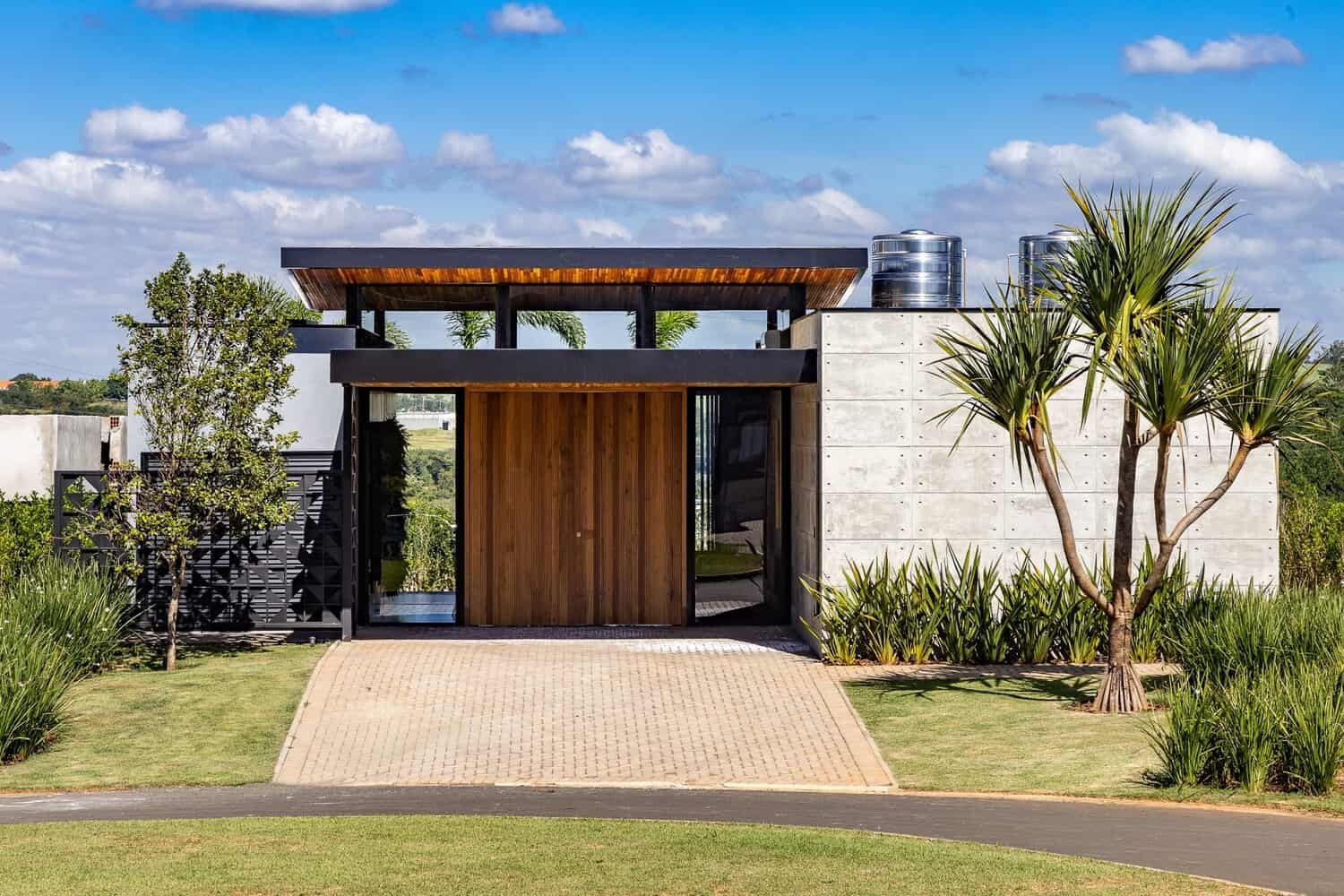 Modern minimalist house with concrete and wood exterior, landscaped garden, and tropical plants, showcasing contemporary architecture and innovative design.