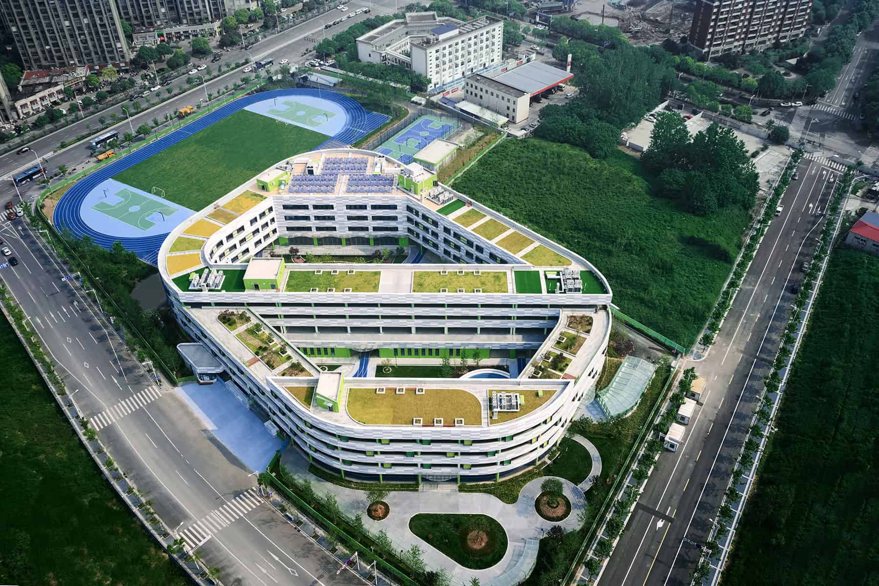 Modern architectural design of a multi-story educational building with rooftop gardens and green spaces, featuring innovative construction and sustainable urban development elements.