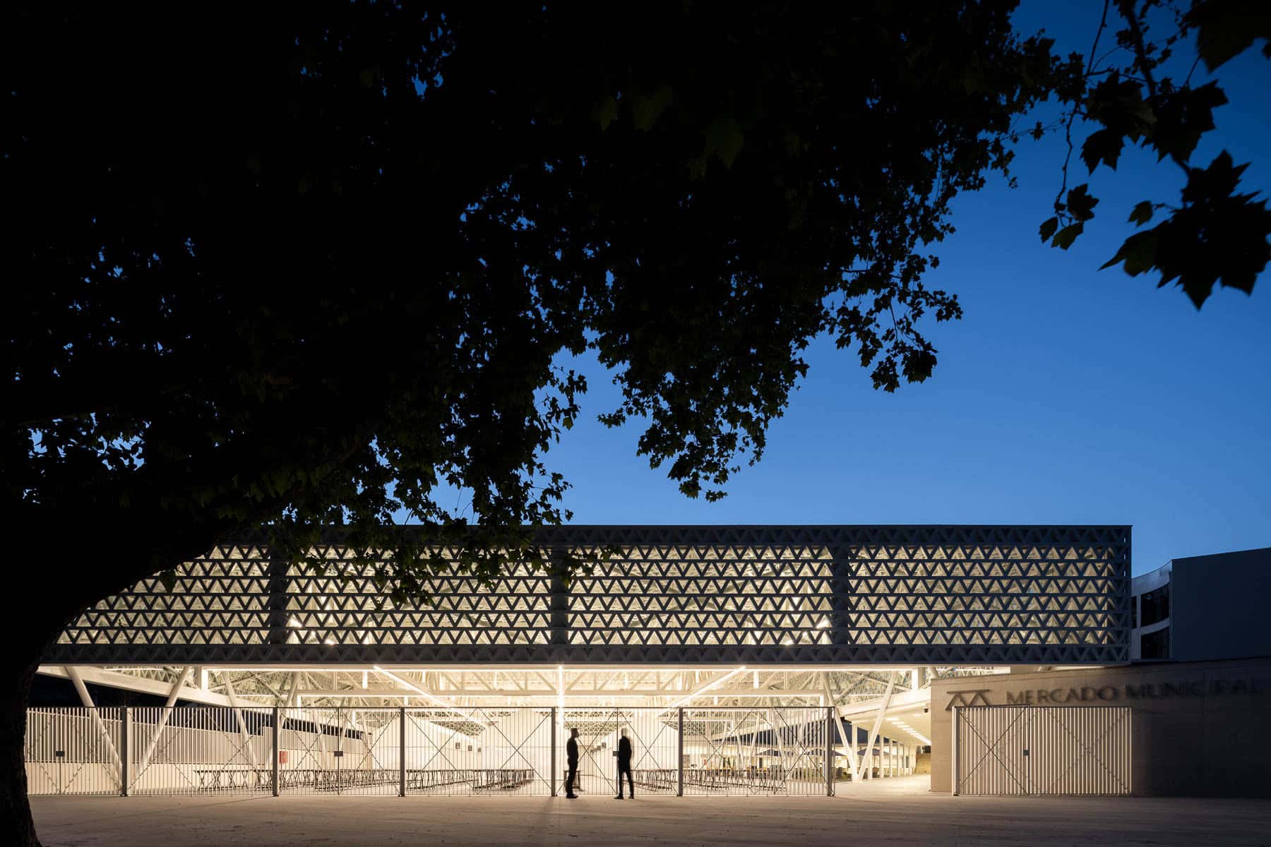 Contemporary architecture at Mercado Municipal with illuminated modern design, geometric facade, and dusk lighting creating an urban vibe. Perfect example of innovative market building design.