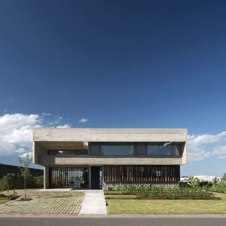 Contemporary concrete modern house with minimalist architecture and large glass windows under clear blue sky.