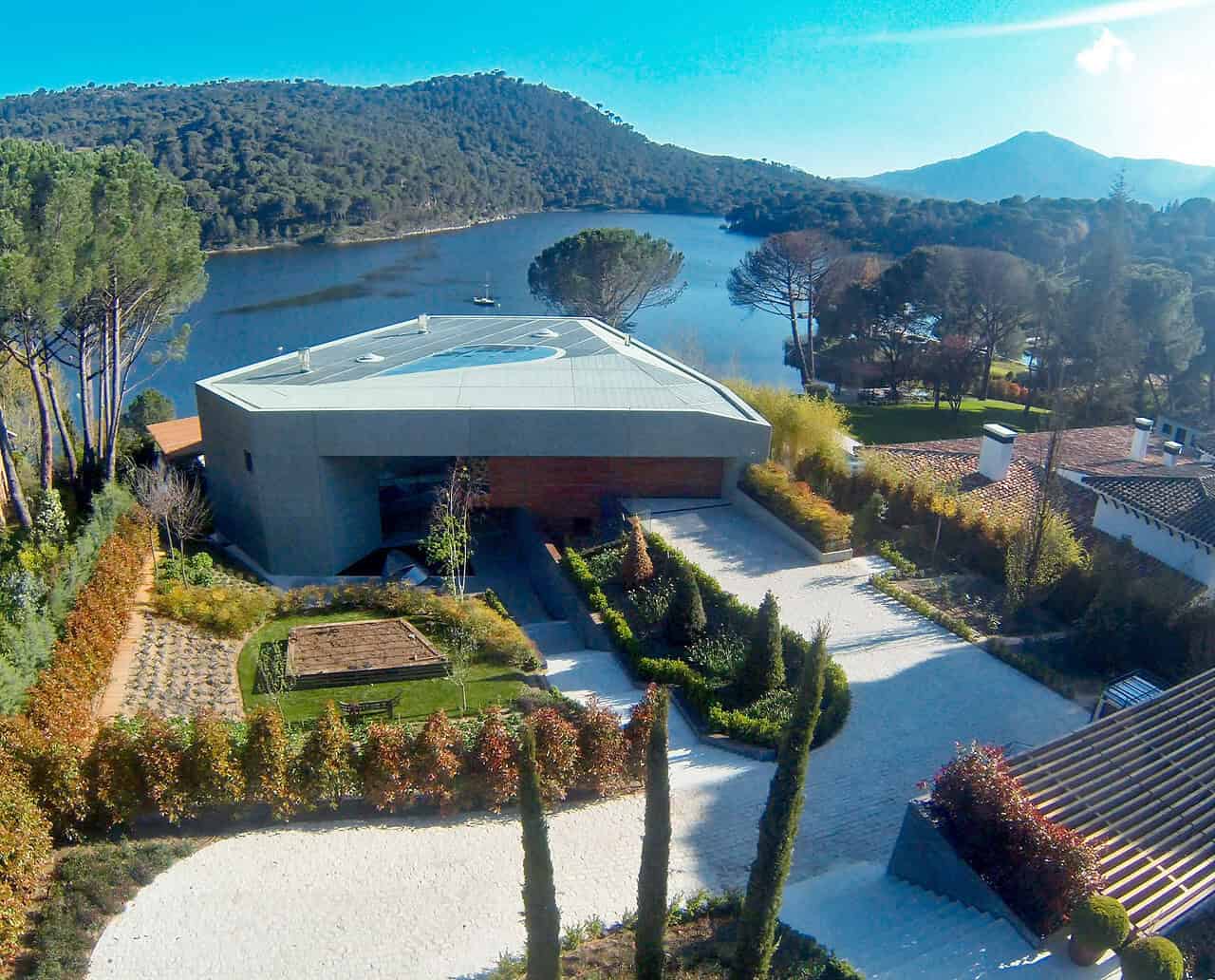 Modern lakeside house with contemporary architecture and surrounding landscaped gardens, offering stunning views of the lake and natural landscape in a serene setting.