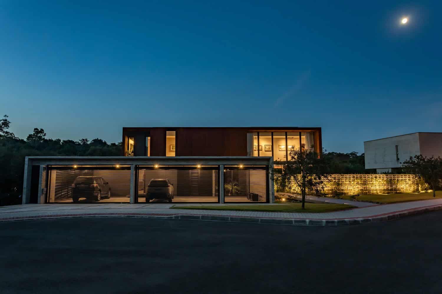 Modern contemporary house with sleek architectural design and illuminated garage at dusk, featuring clean lines, large glass windows, and stylish exterior lighting for a luxurious home aesthetic.