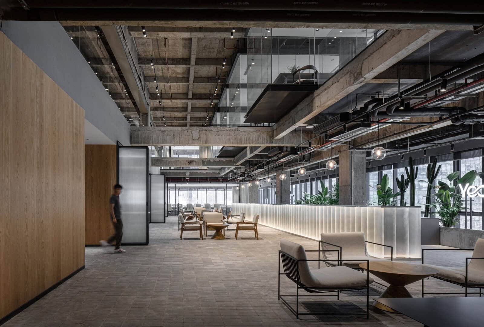 Modern industrial office interior with exposed concrete beams, large windows, and contemporary furniture, showcasing innovative architecture and stylish design.