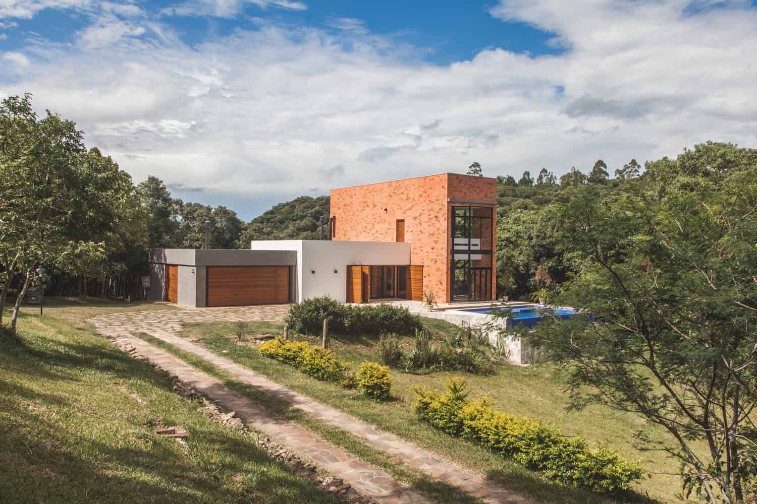 Modern contemporary house with mixed materials including brick and concrete, large windows, and lush landscaping, showcasing innovative architectural design and outdoor living spaces.