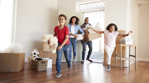 Excited Family Carrying Boxes Into New Home On Moving Day