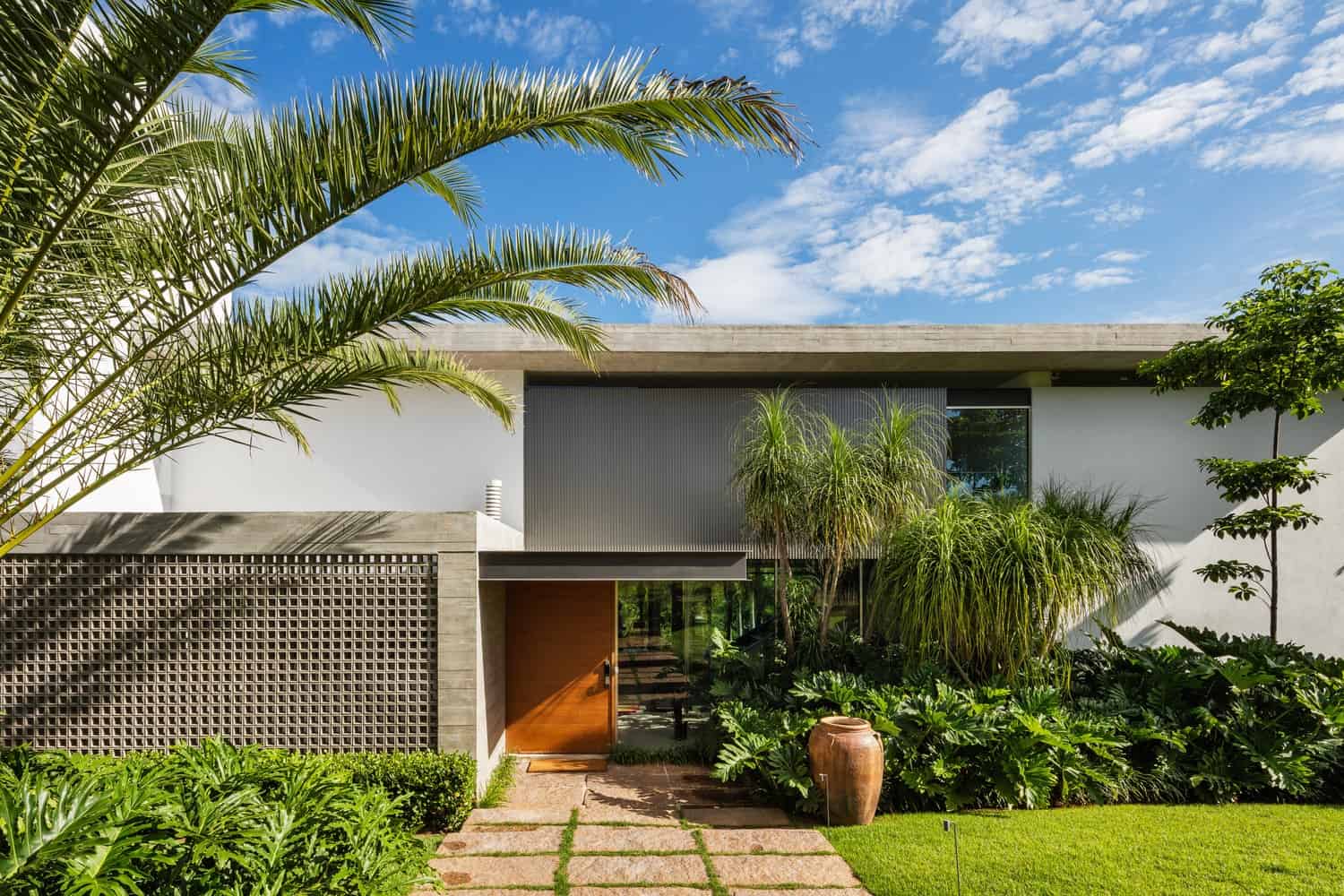Modern minimalist house with lush tropical landscaping and contemporary architectural design.