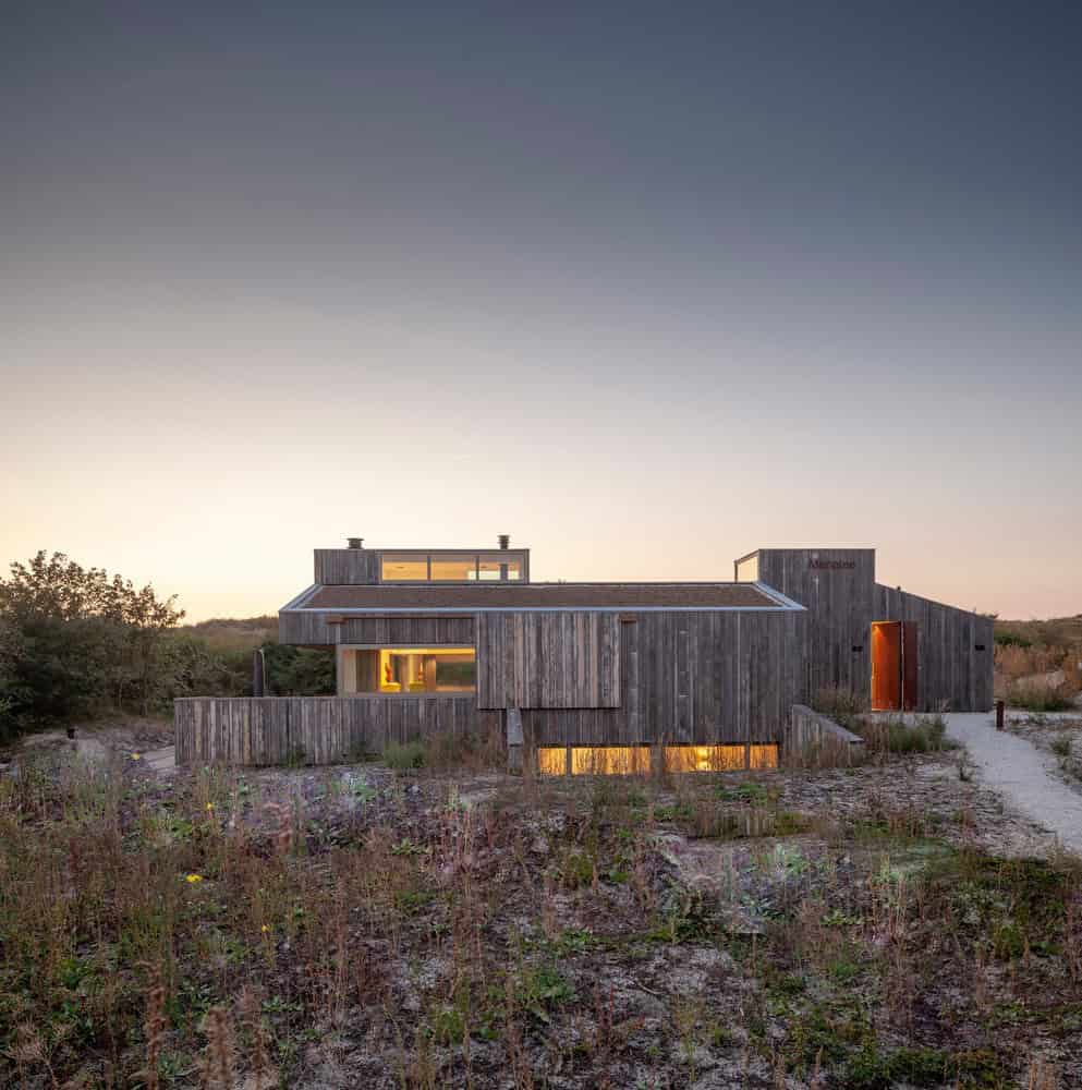 Modern wooden house with minimalist design, set in natural landscape during sunset, showcasing innovative architecture and eco-friendly materials for contemporary home design.