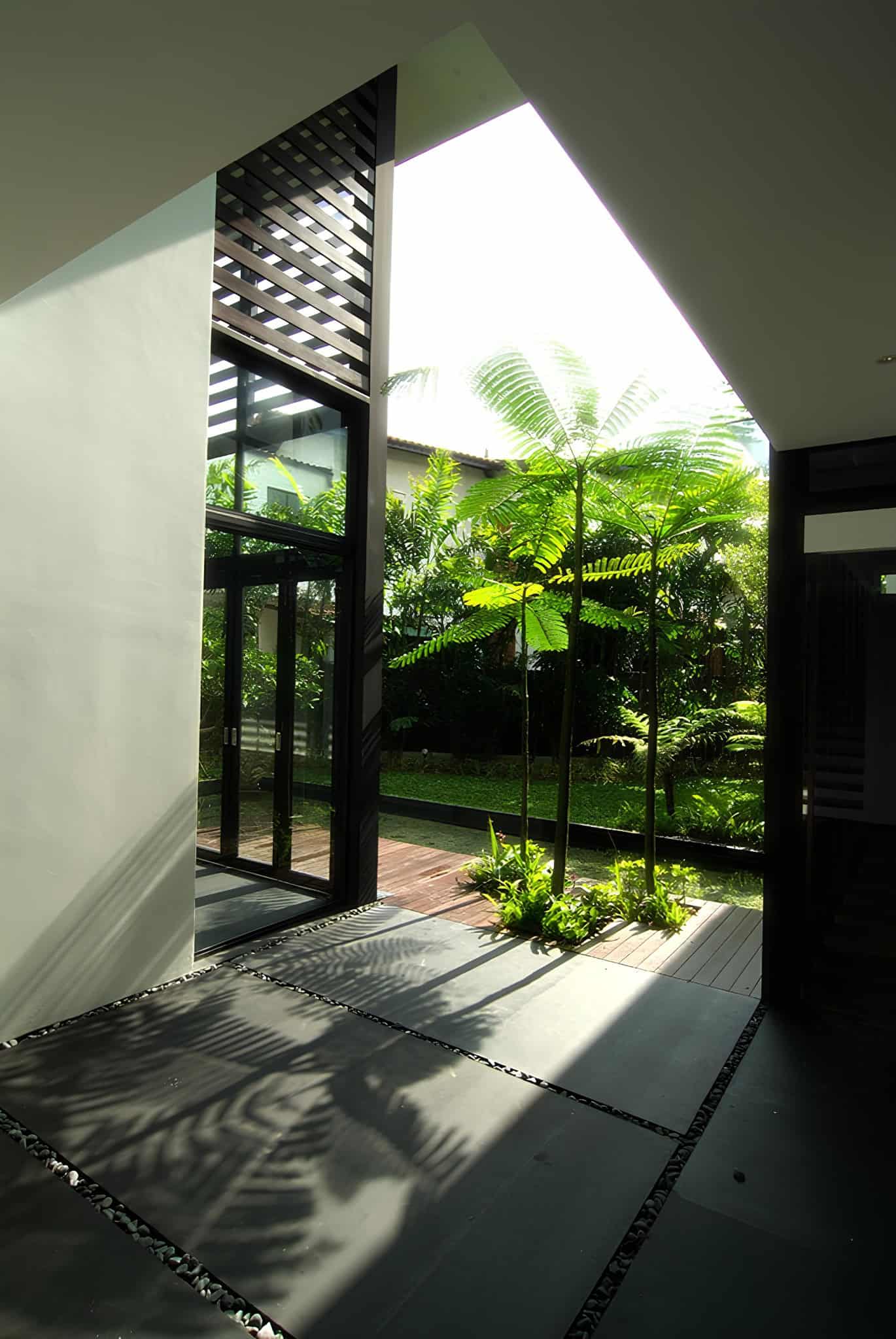 Jalan Merlimau Garden Entrance Light View toward the garden from inside Jalan Merlimau, framed by a dramatic roof opening.