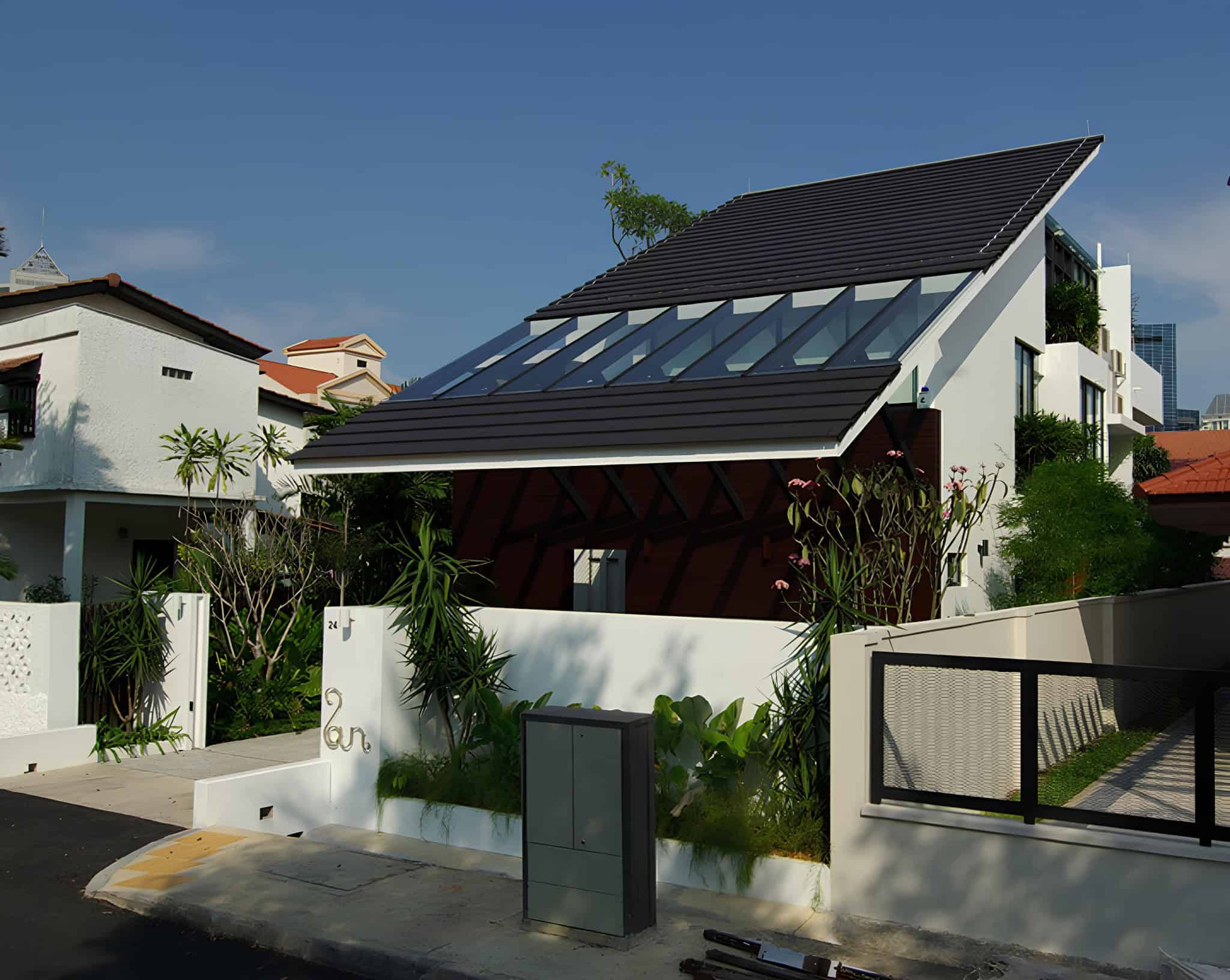 Contemporary modern house with sleek design, large glass windows, and a unique sloped roof in a vibrant neighborhood, showcasing innovative architecture and stylish outdoor landscaping.