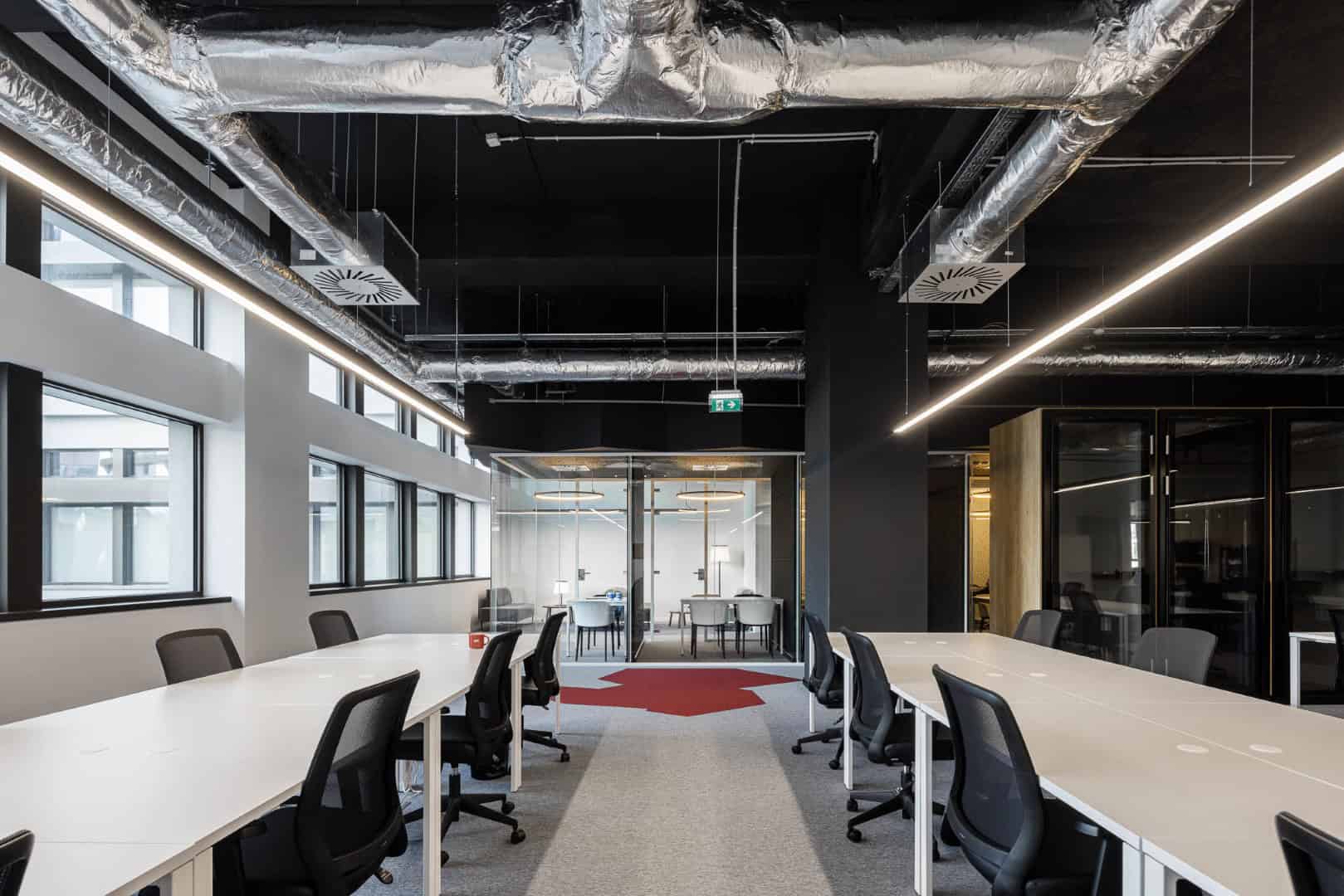 Modern office interior design with open workspace, contemporary furniture, sleek lighting, and industrial ceiling elements focusing on innovative architecture and interior architectural design.