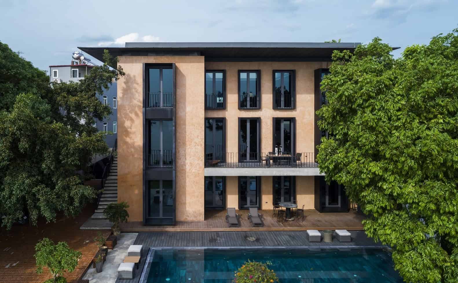 Contemporary modern house with large windows, a patio, and a swimming pool, surrounded by greenery and trees, showcasing luxurious architecture and outdoor living design.