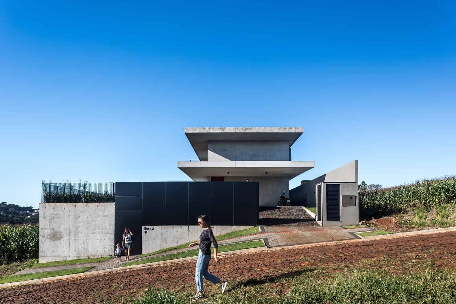 Contemporary modern house with minimalist concrete architecture and sleek design elements, set against a bright blue sky, featuring an innovative structure and stylish outdoor space.