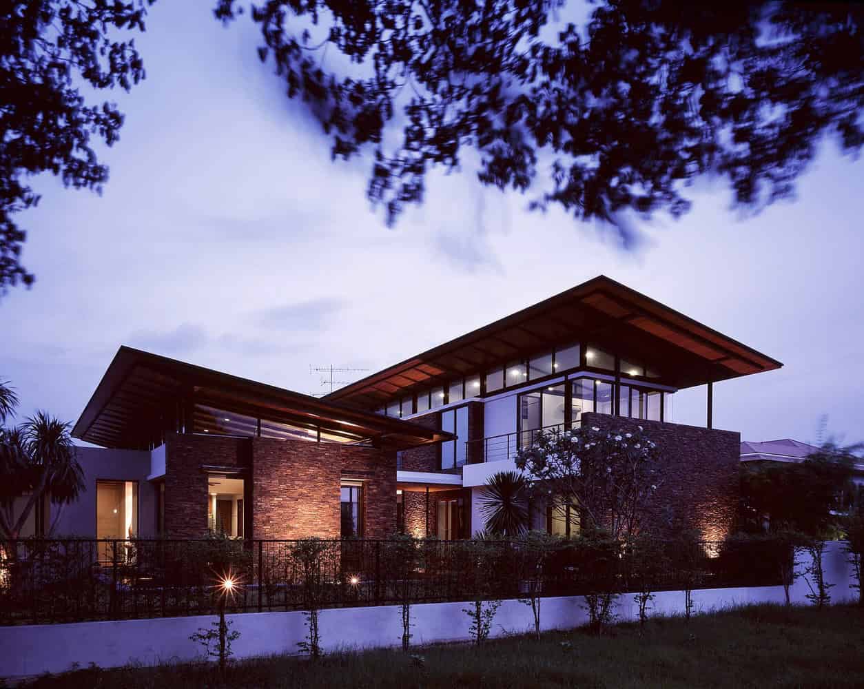 Modern contemporary house with large glass windows and brick accents showcasing innovative architectural design at dusk.