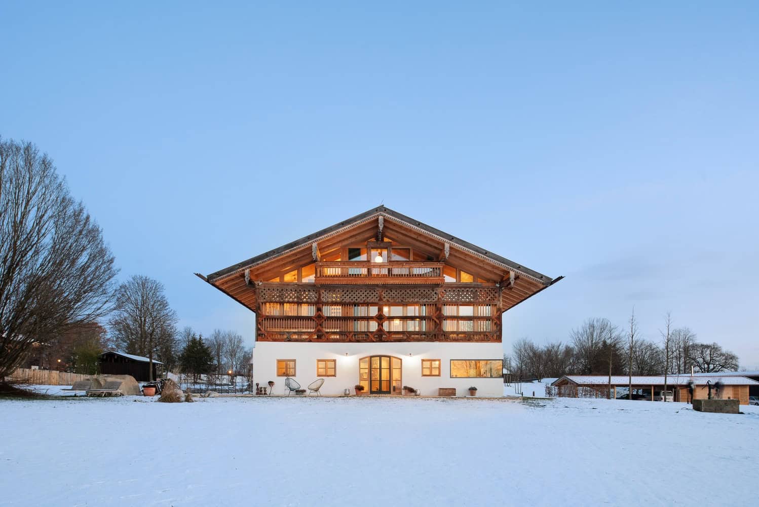 Rustic chalet-style house with wooden balcony and large windows showcased in winter landscape, highlighting cozy architecture, outdoor living space, and scenic snowy surroundings.