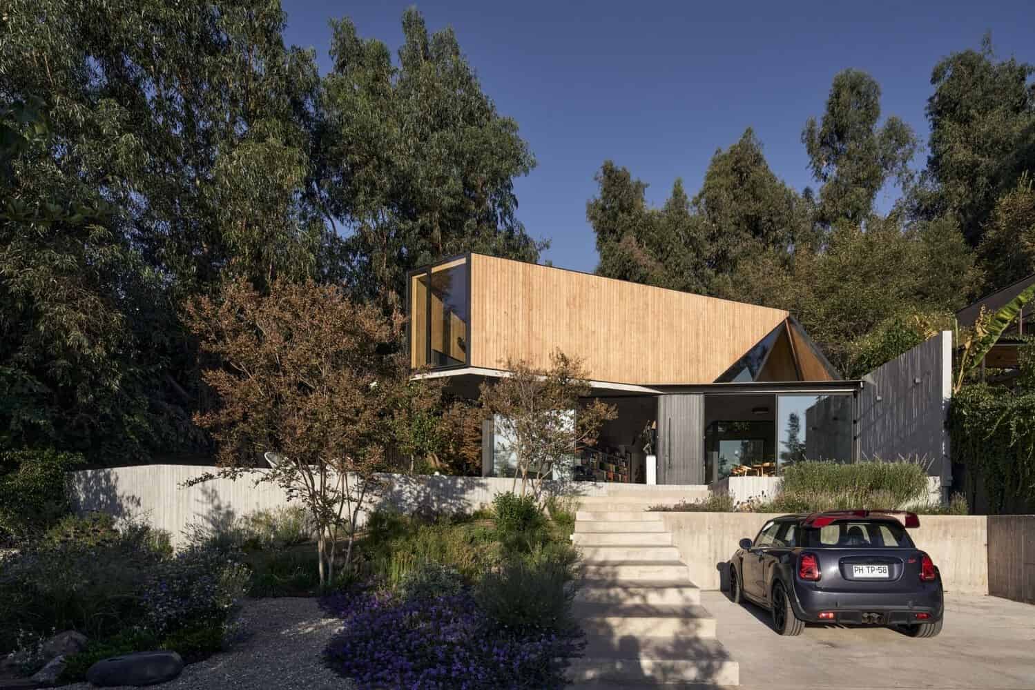 Contemporary modern house with wooden and metal exterior, large glass windows, landscaped garden, and driveway with car, surrounded by tall trees, illustrating innovative residential architecture.