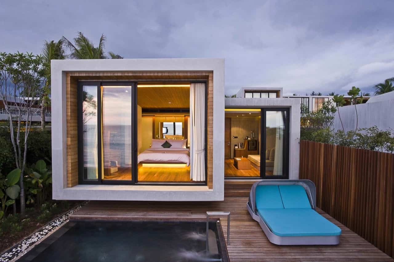Modern luxury tiny house with large glass sliding doors, overlooking the pool area, featuring contemporary architecture and innovative interior design for a stylish vacation retreat.