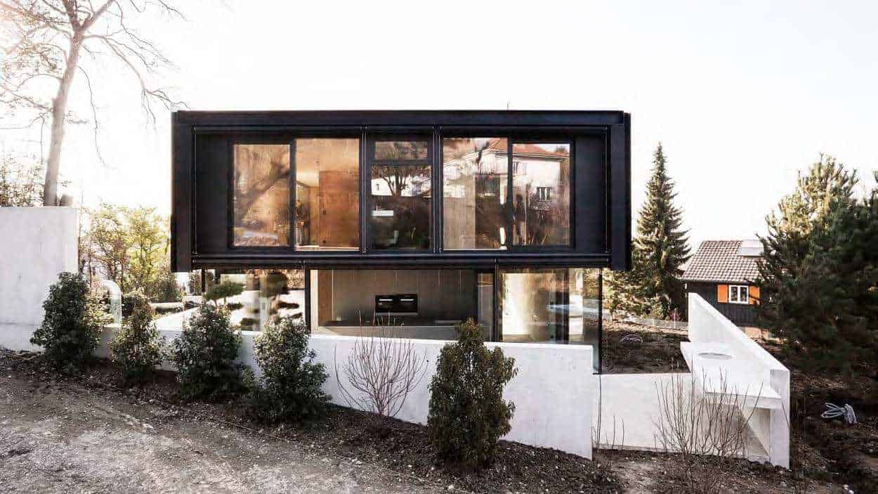 Contemporary modern house with black and glass exterior, minimalist architectural design, and landscaped garden showcasing innovative architecture art designs.