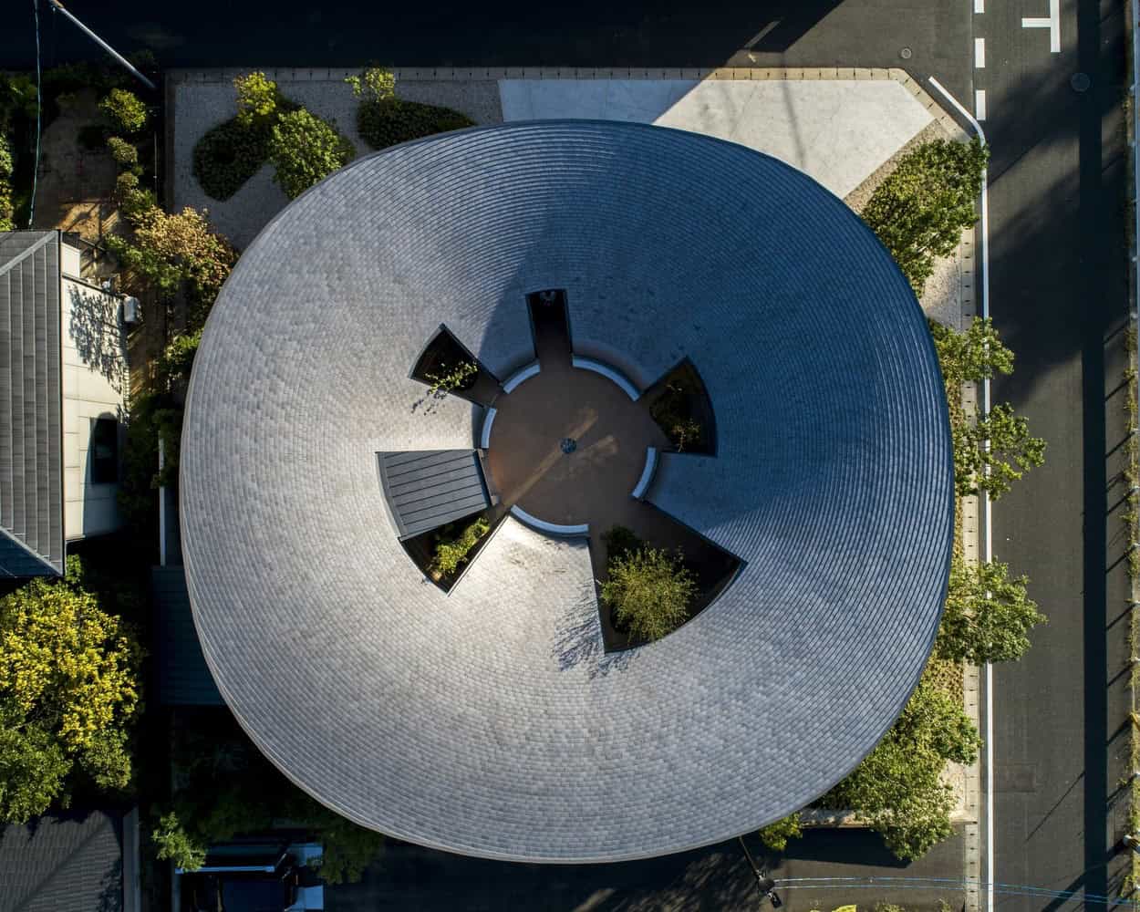 Modern circular architectural building with unique roof design in an urban setting.