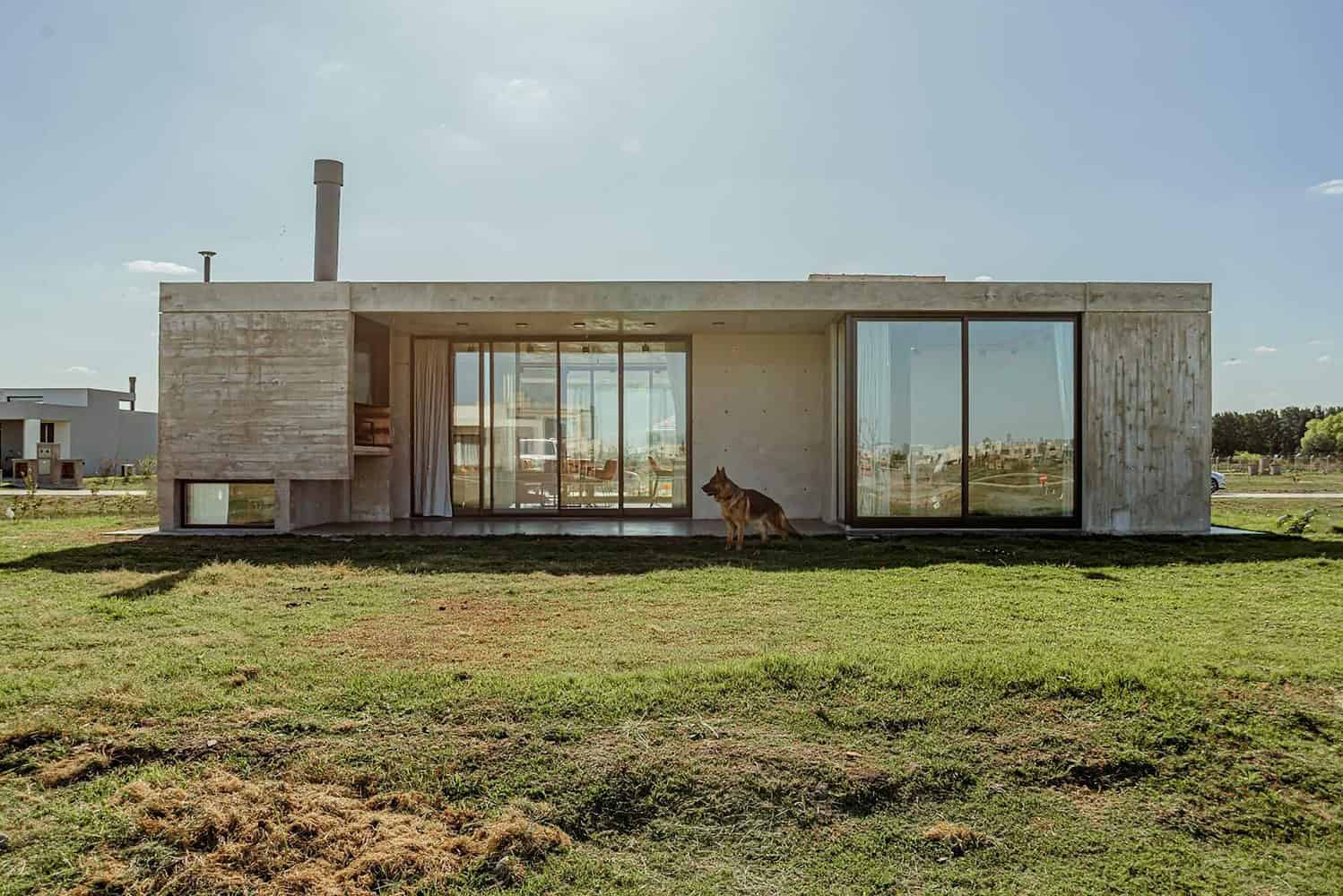Modern minimalist concrete house with large glass sliding doors and outdoor lawn, showcasing innovative architecture design, contemporary home exterior, and eco-friendly construction.