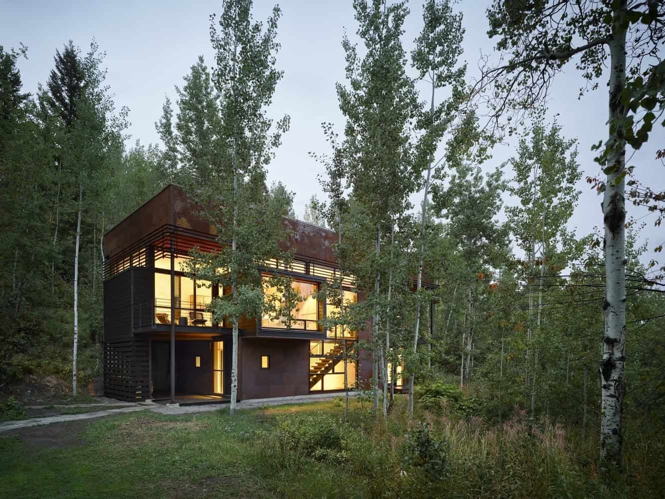 Modern eco-friendly house nestled in a lush forest with large glass windows and contemporary architectural design. Perfect for nature lovers seeking sustainable living.