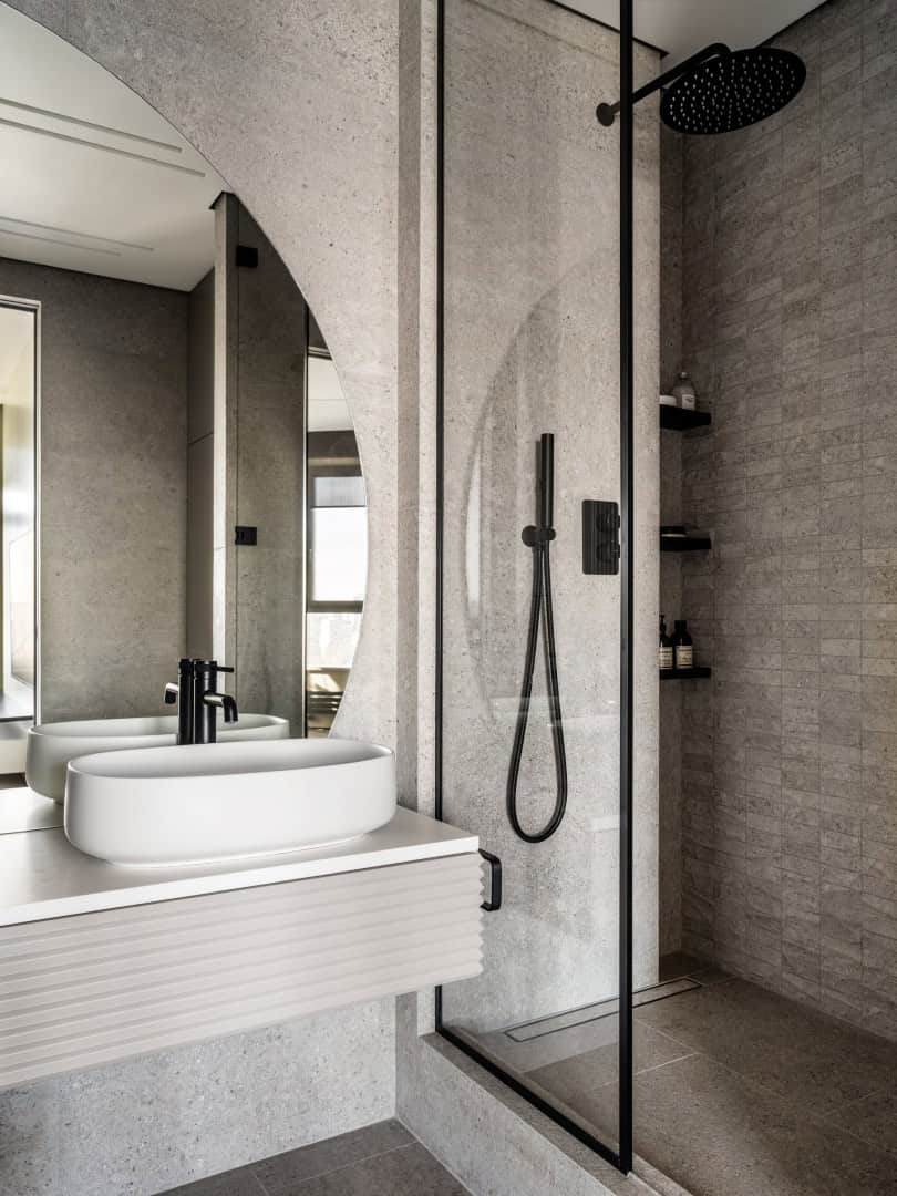 Apartment with a Glass Home Office / Alexander Tischler / Russia Guest bathroom with round mirror and concrete-textured tile