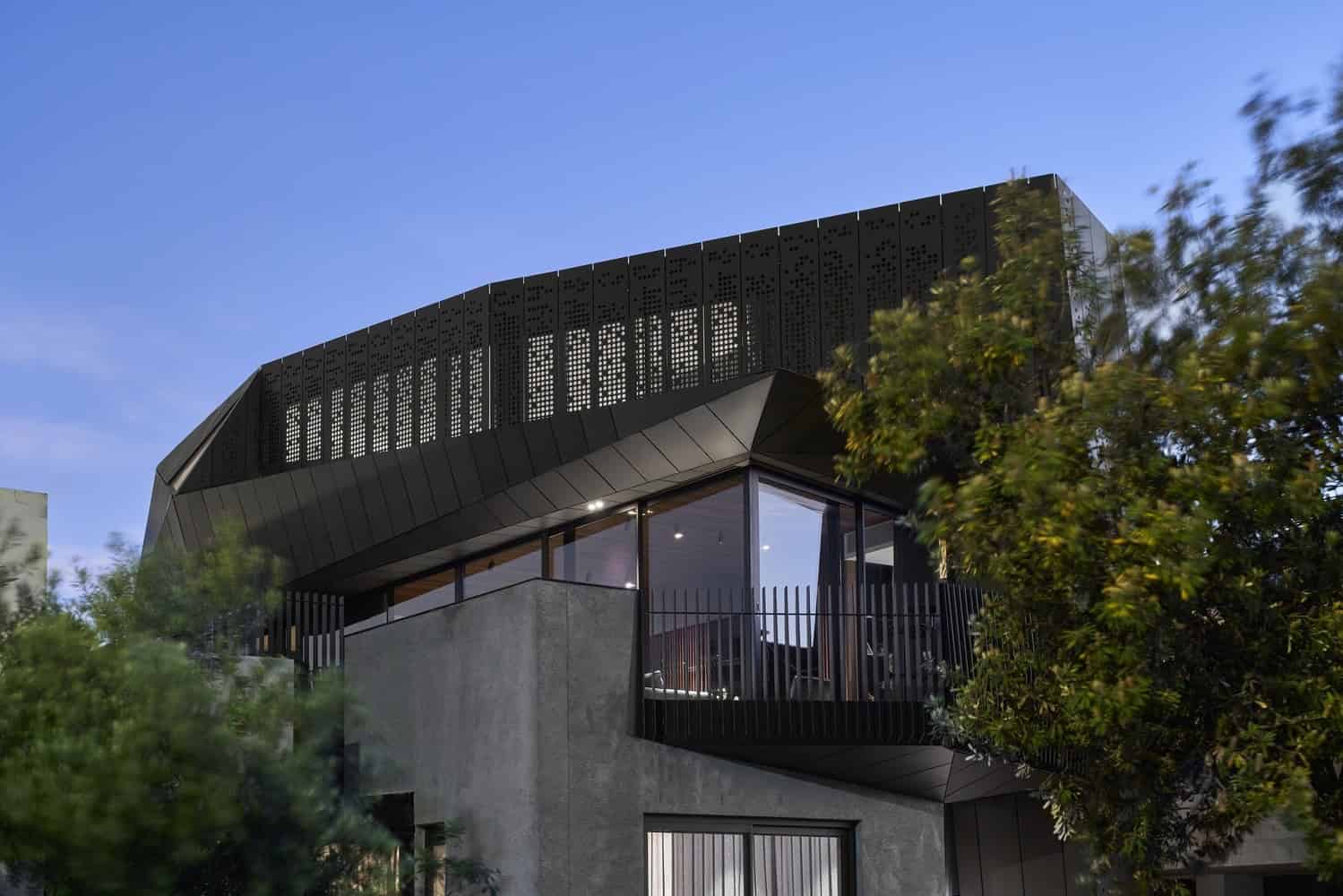 Futuristic modern architecture house with sleek black facade, large windows, and innovative design elements, surrounded by lush greenery under a clear blue sky.
