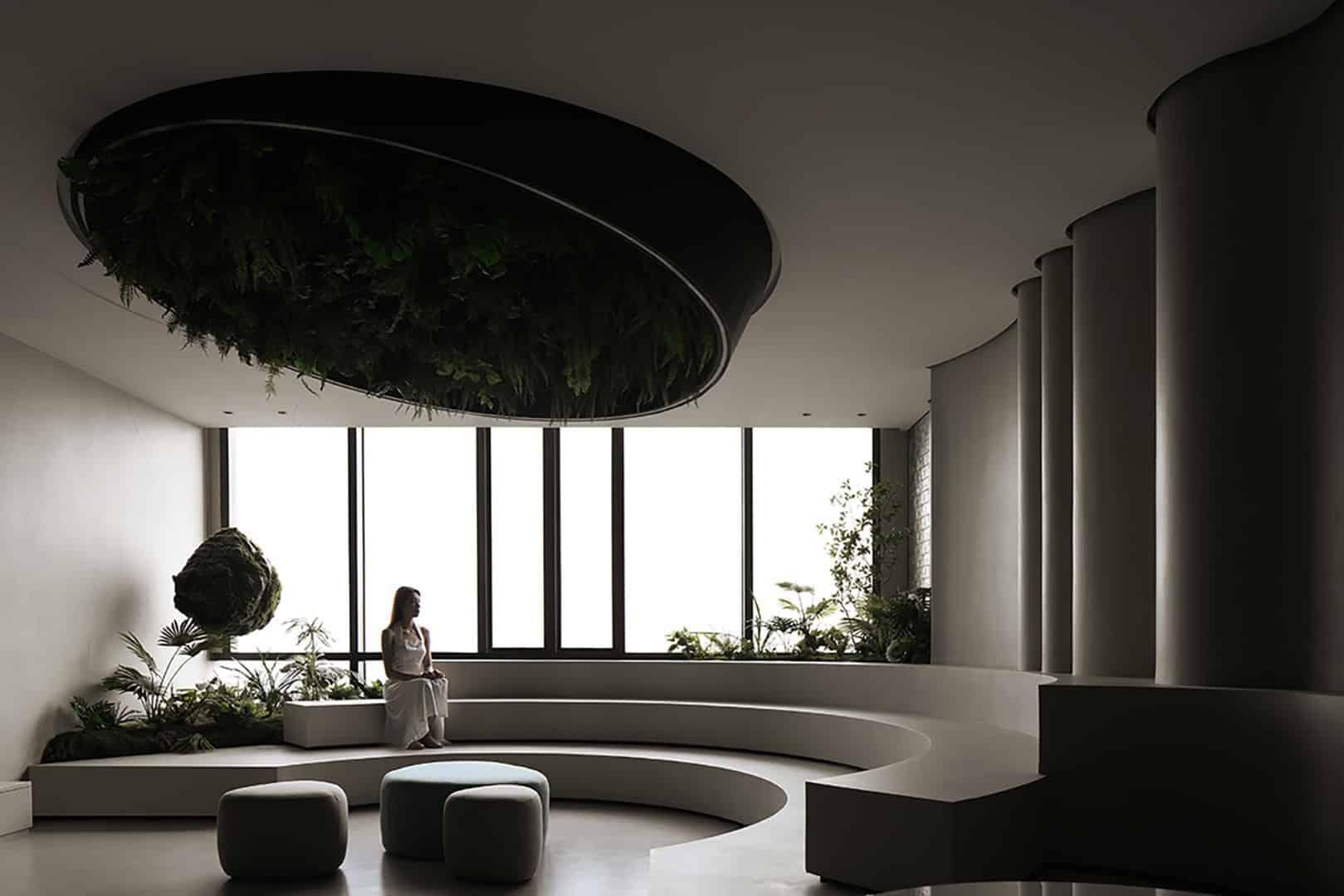 Modern minimalist interior with large floor-to-ceiling windows, stylish seating, and decorative greenery creating a serene and contemporary space.