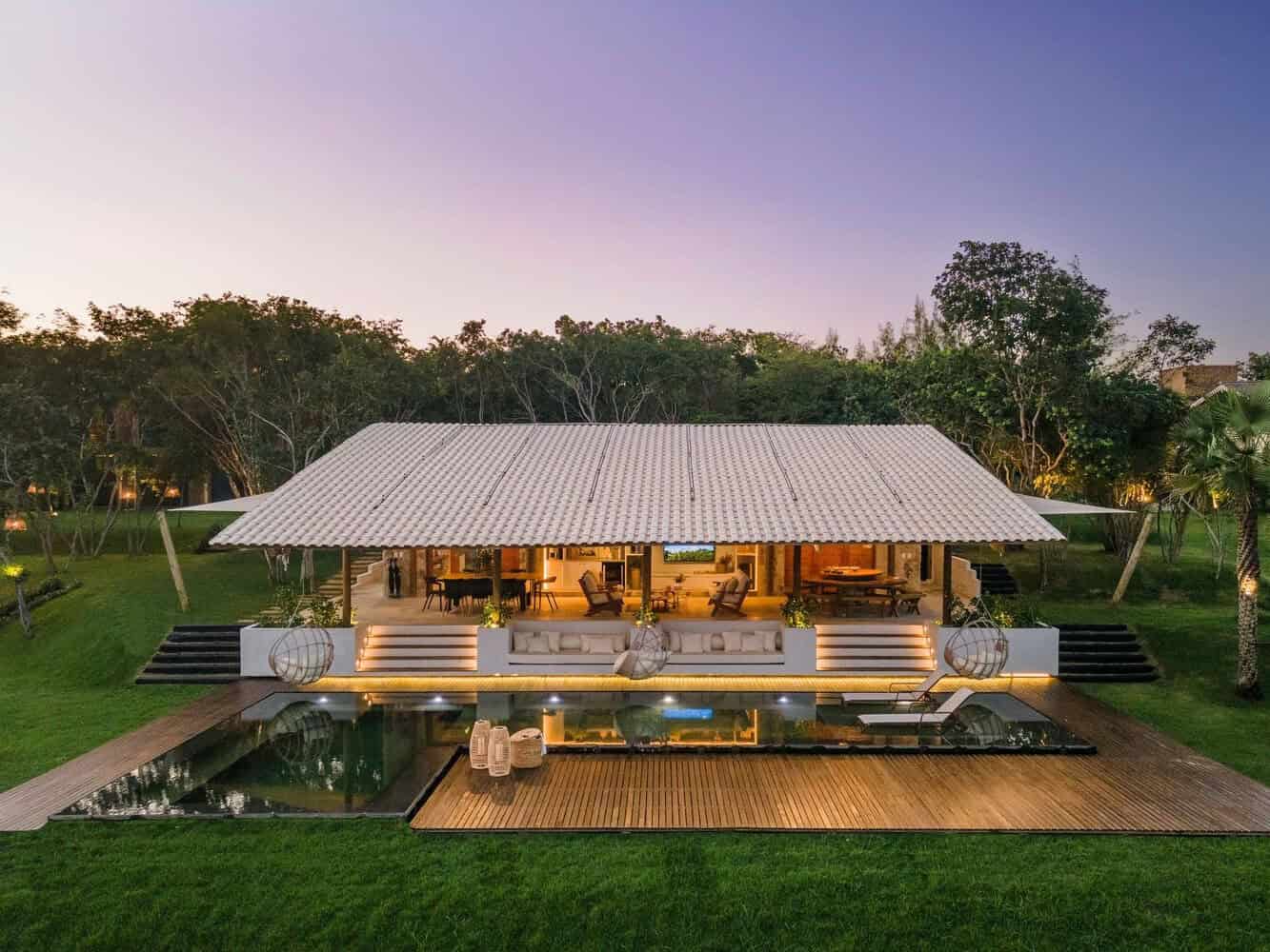 Modern tropical villa with open-plan living, lush gardens, and a pool, perfect for luxury outdoor entertainment and elegant interior design.