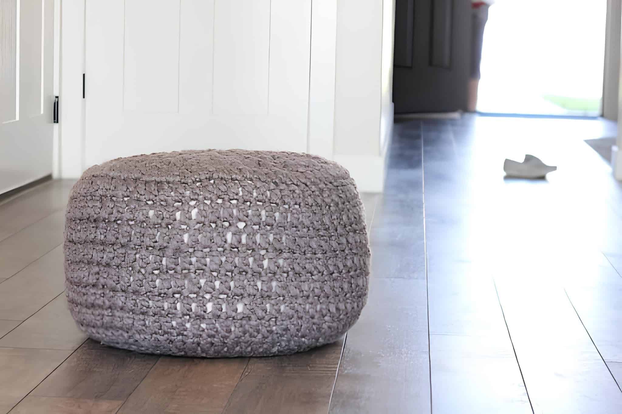 Soft Bulky Yarn Crochet Floor Pouf Hand-crocheted pouf made from chunky gray yarn placed in a modern hallway