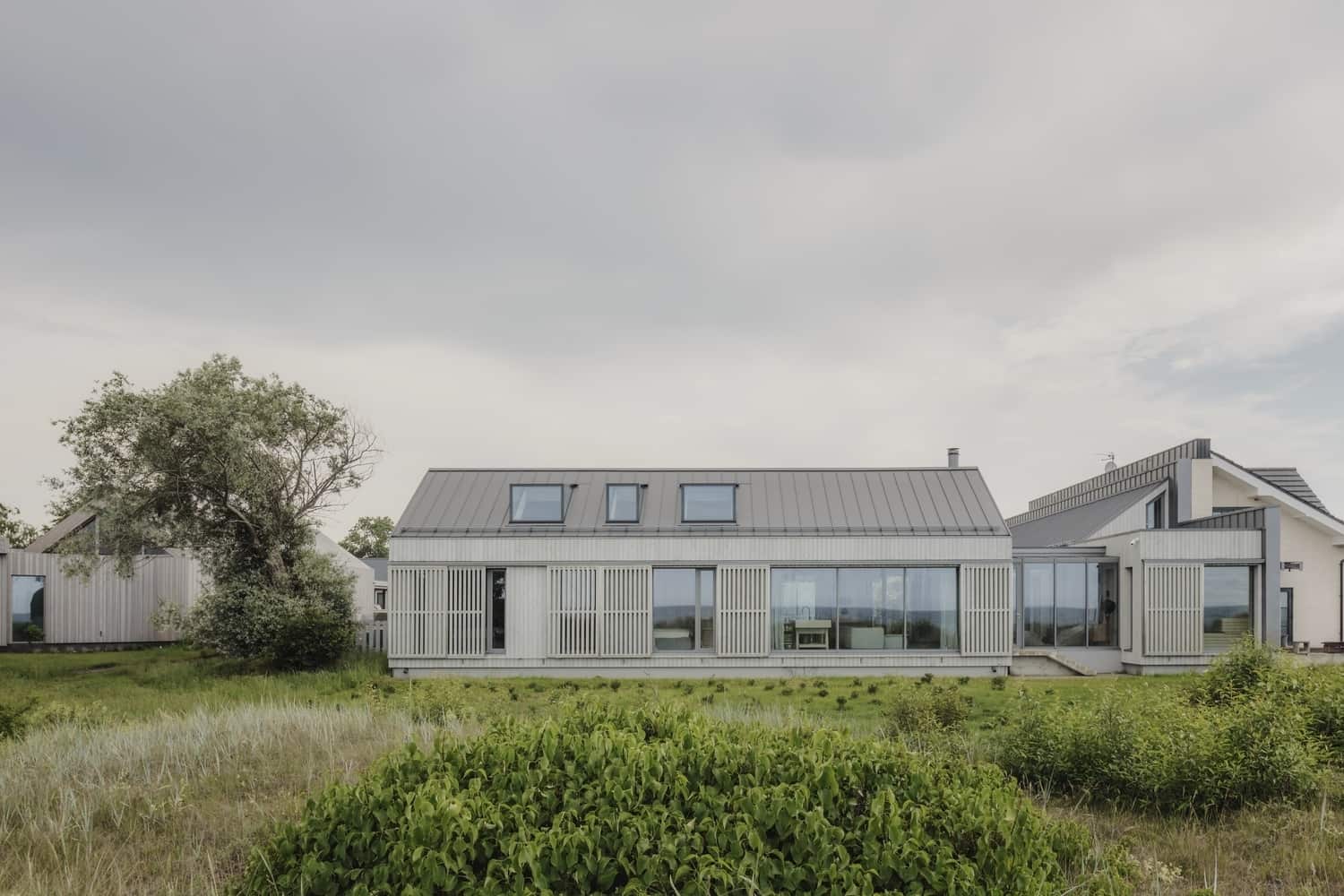 Contemporary modern house with sleek white exterior, large glass windows, and minimalist architectural design, set in a lush green landscape, showcasing innovative architecture and home design.