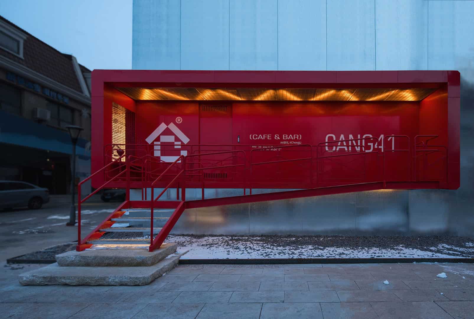 Modern red container café and bar with contemporary architecture design, illuminated in urban setting, featuring bold color and innovative structure, perfect for trendy social spots.