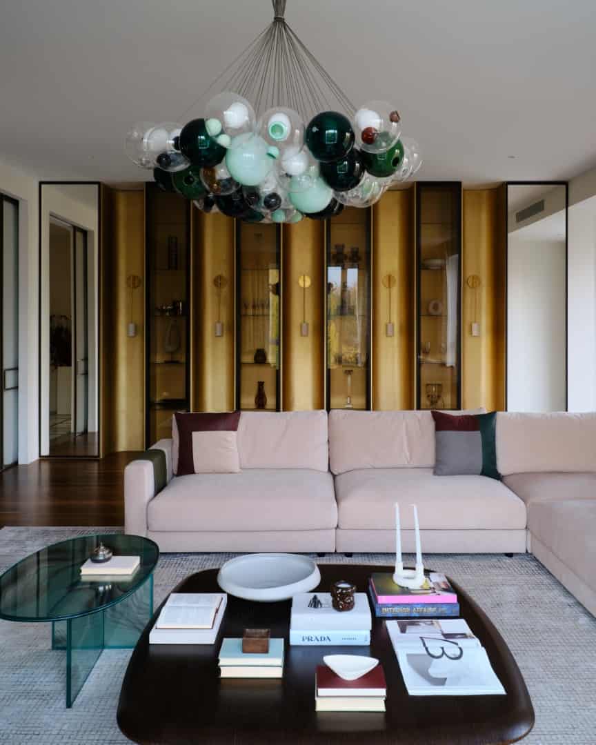 Modern living room interior with contemporary chandelier, elegant beige sofa, and stylish gold display cabinets, showcasing luxury home design and interior decor ideas.