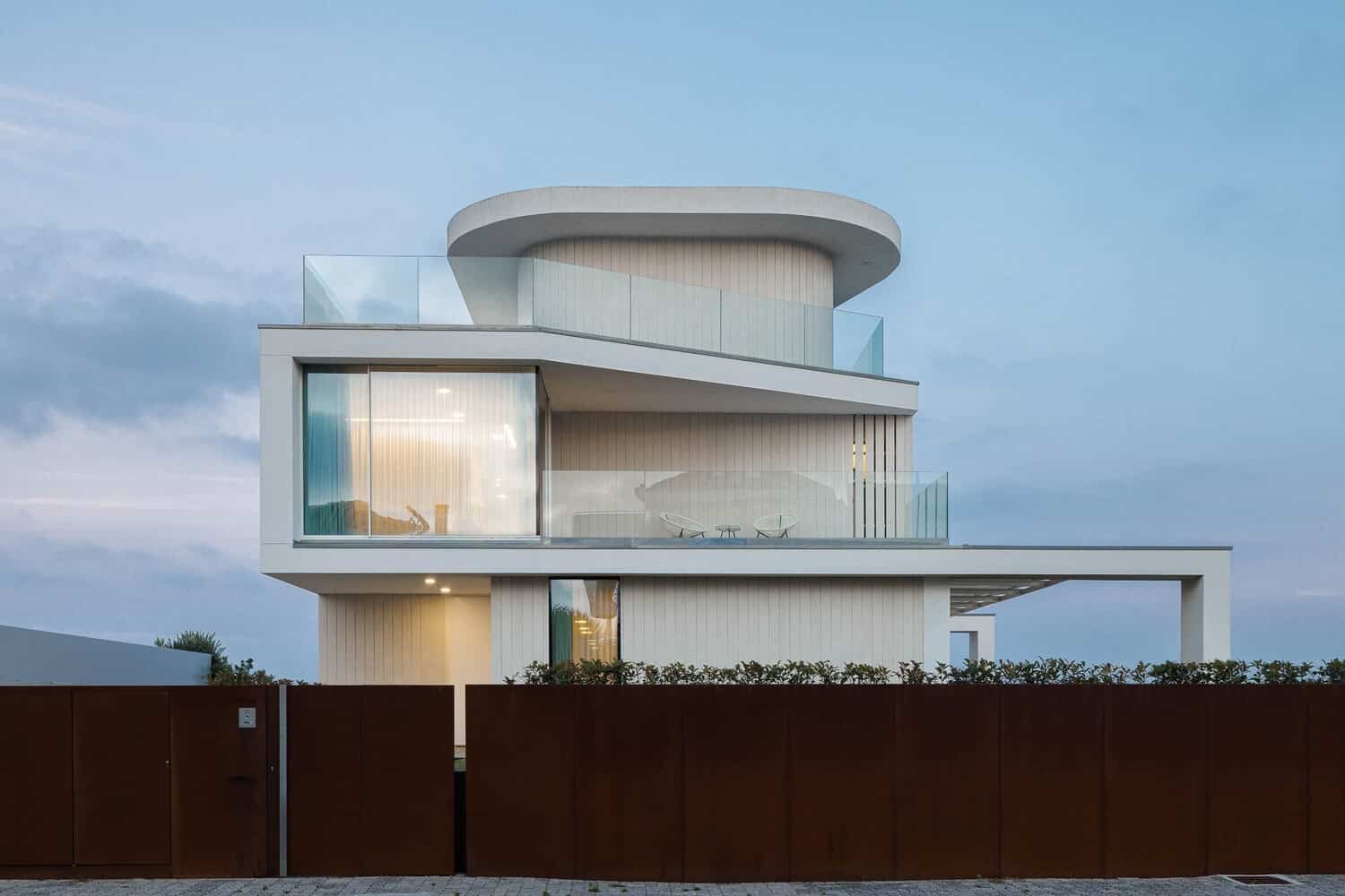 Contemporary modern white multi-story house with sleek architecture, glass balconies, and large windows, set against a blue sky. Features clean lines, open terraces, and minimalist design, perfect for luxury architecture design.